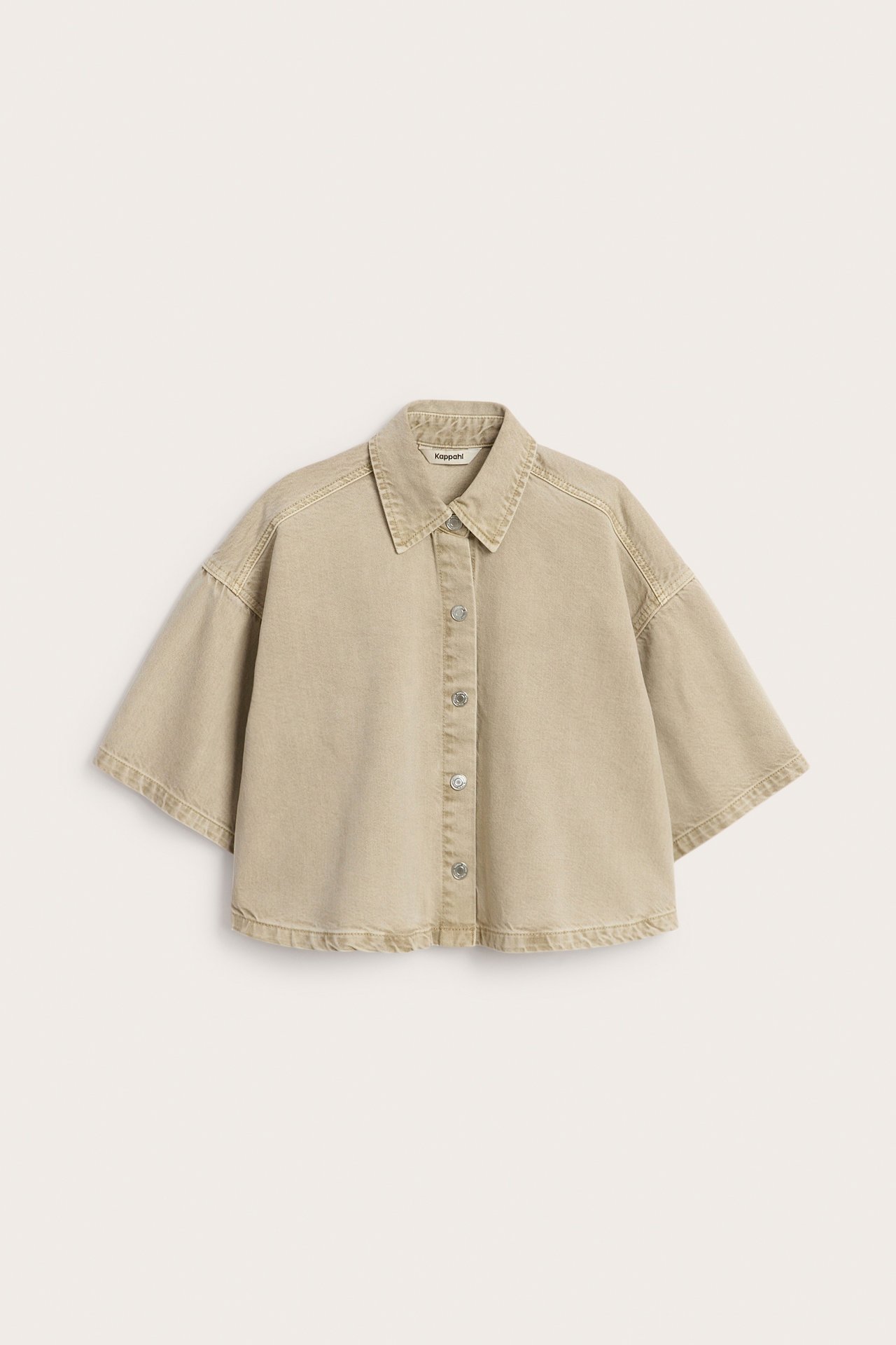 Edestä näkymä vaaleanruskeasta twillpaidasta, jossa lyhyt, väljä istuvuus, leveät hihat ja hopeiset napit.