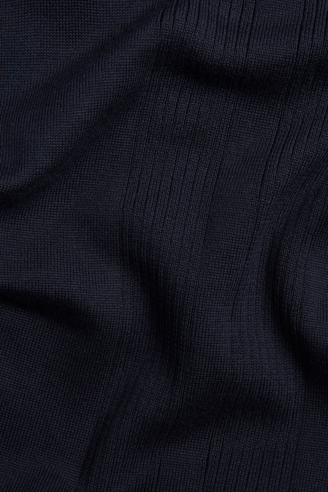 Närbild av mörkblått, ribbstickat bomullstyg från en pikétröja.