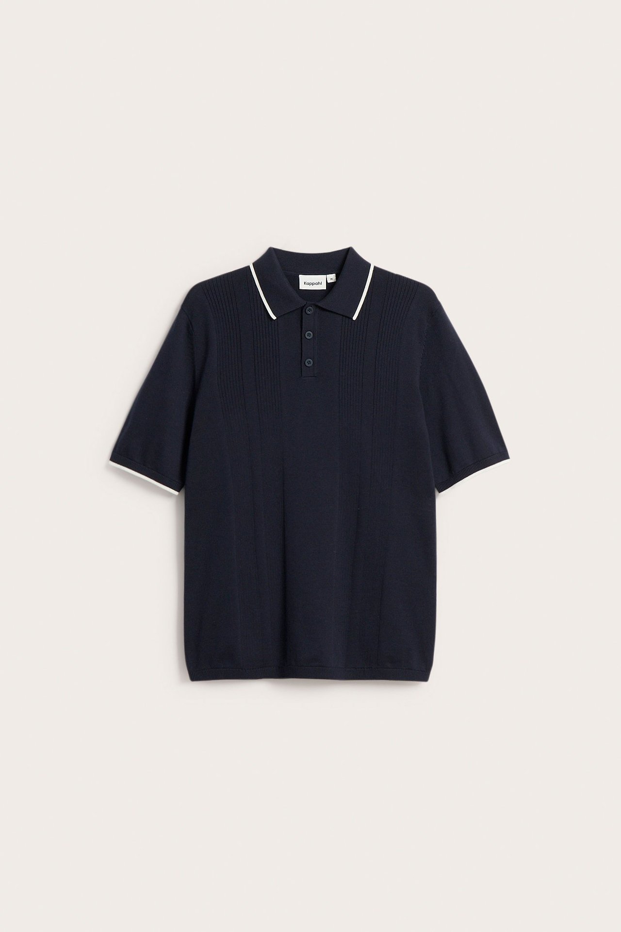 Edestäpäin: Tumman sininen neulottu pikeepaita kolmella napilla, valkoiset raidat kauluksessa ja hihansuissa.