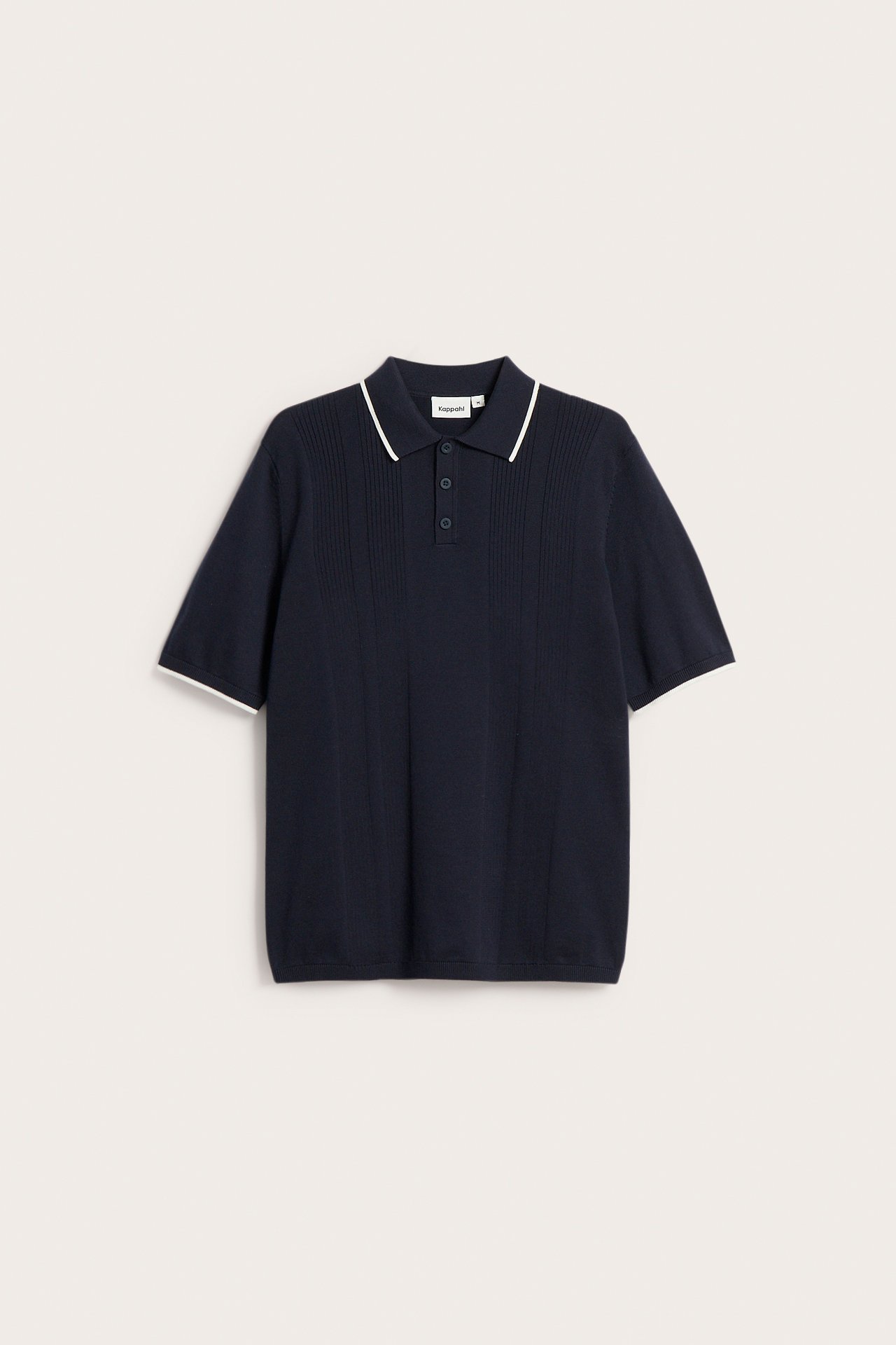 Framifrån: Mörkblå stickad pikétröja med tre knappar och vita kontrasterande ränder på krage och ärmslut.