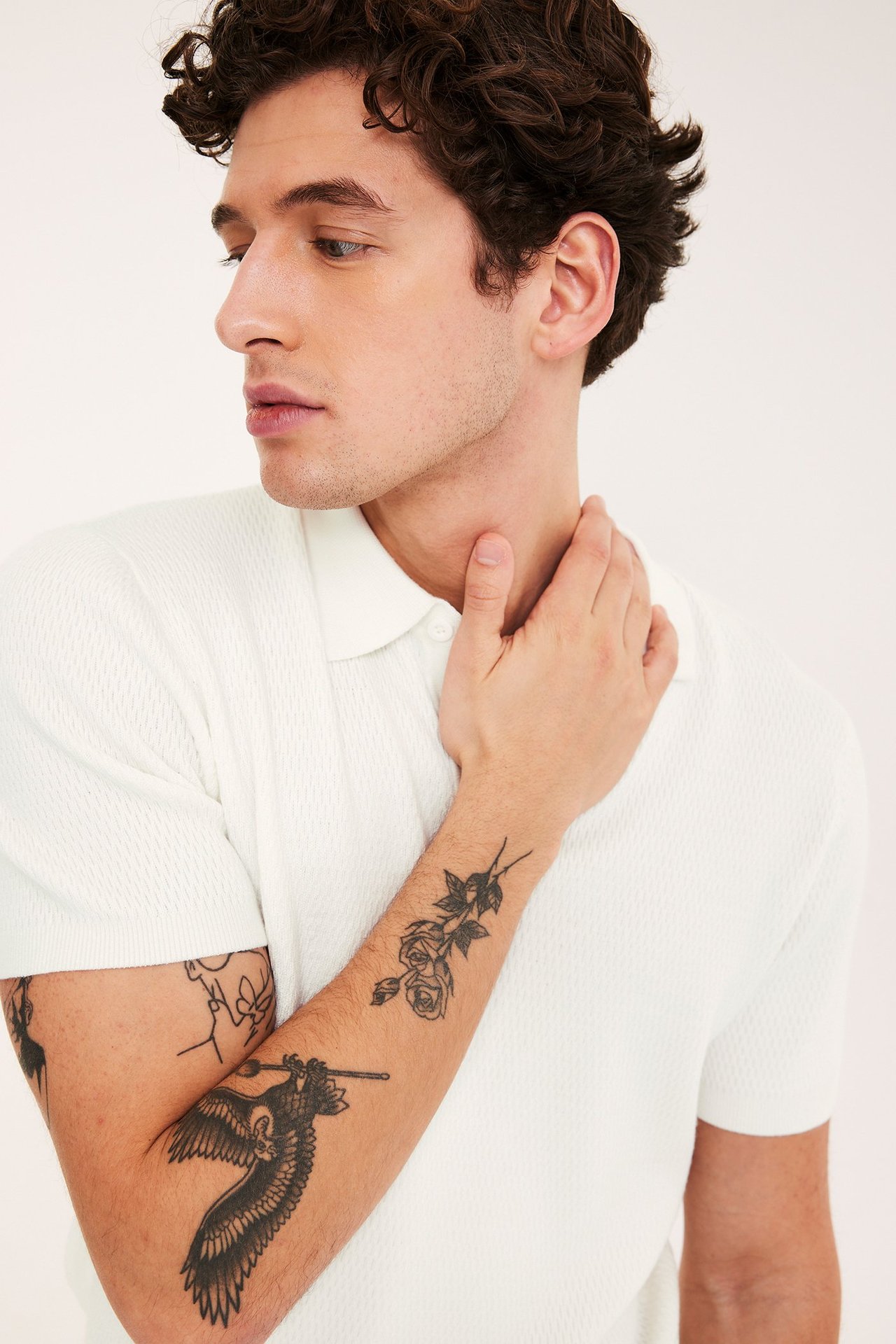 Nærbilde, sidevisning: Mann i offwhite strukturstrikket kortermet piké med krage.