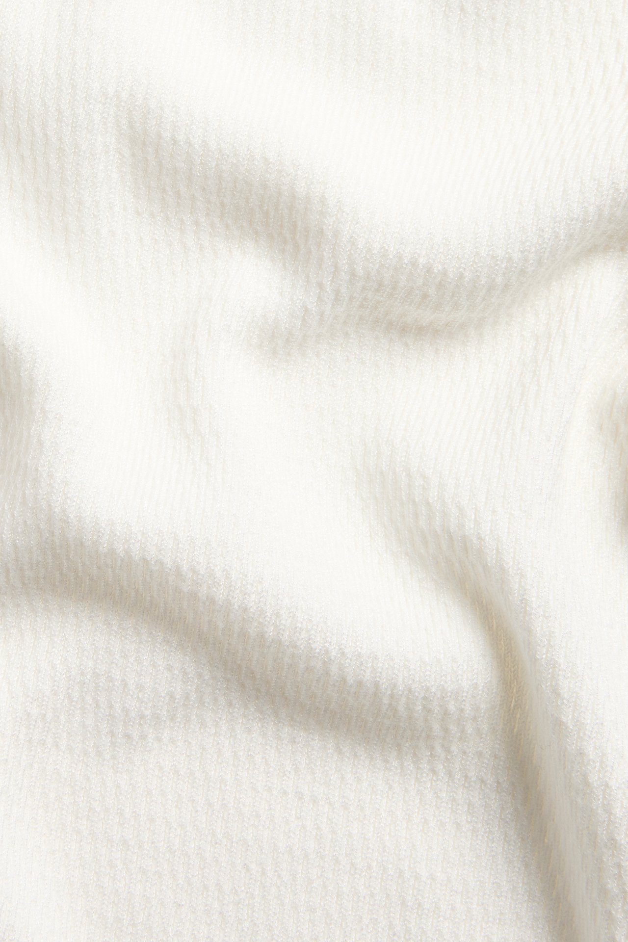 Närbild av offwhite strukturstickat tyg från en pikétröja.