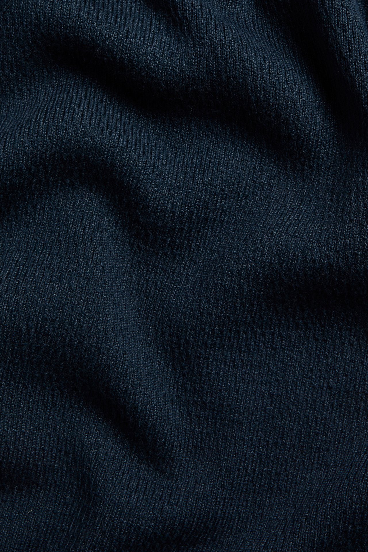 Närbild av ett mörkblått strukturstickat tyg till en pikétröja.