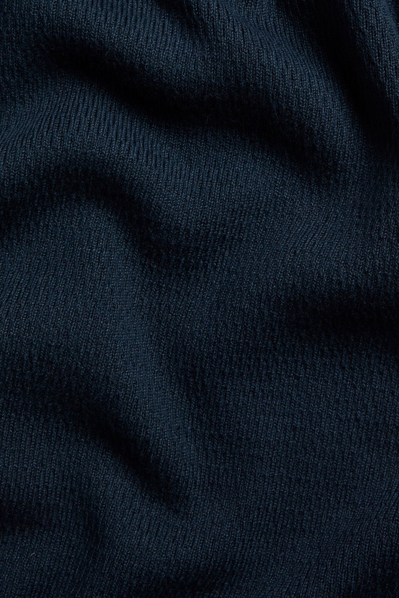 Närbild av ett mörkblått strukturstickat tyg till en pikétröja.