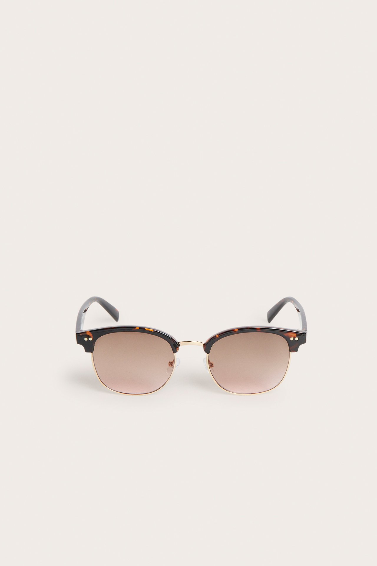 Framifrån, bruna solglasögon med halvbåge i sköldpaddsmönster, guldmetall och bruna glas.