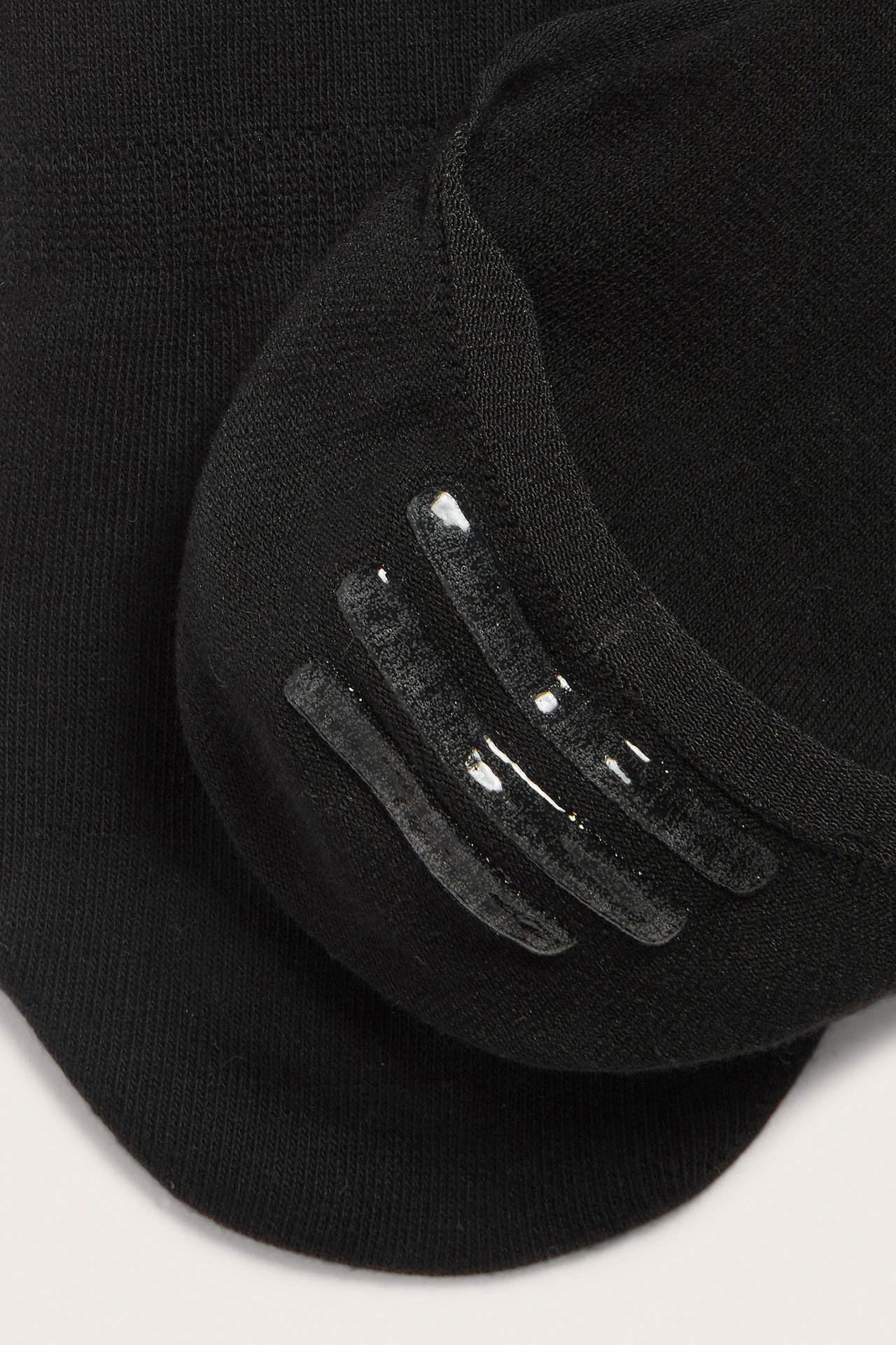 Närbild av en svart osynlig strumpa med silikongrepp på insidan hälen för bättre passform.