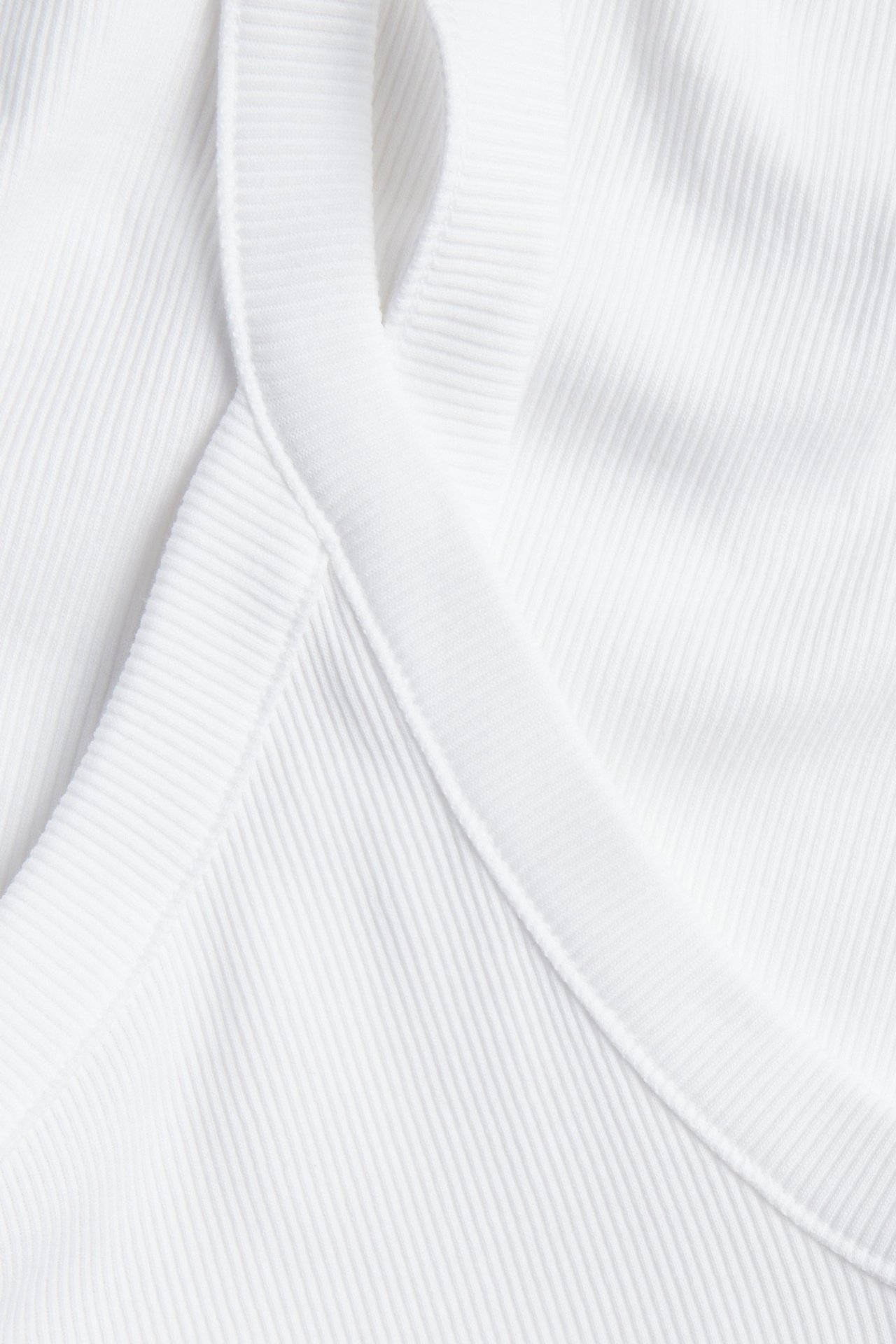 Zbliżenie białego prążkowanego topu na cienkich ramiączkach.