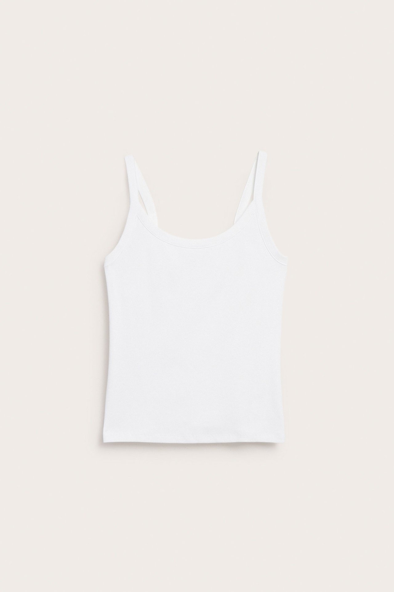 Forfra, en figurnær hvit ribbet singlet med smale skulderstropper.