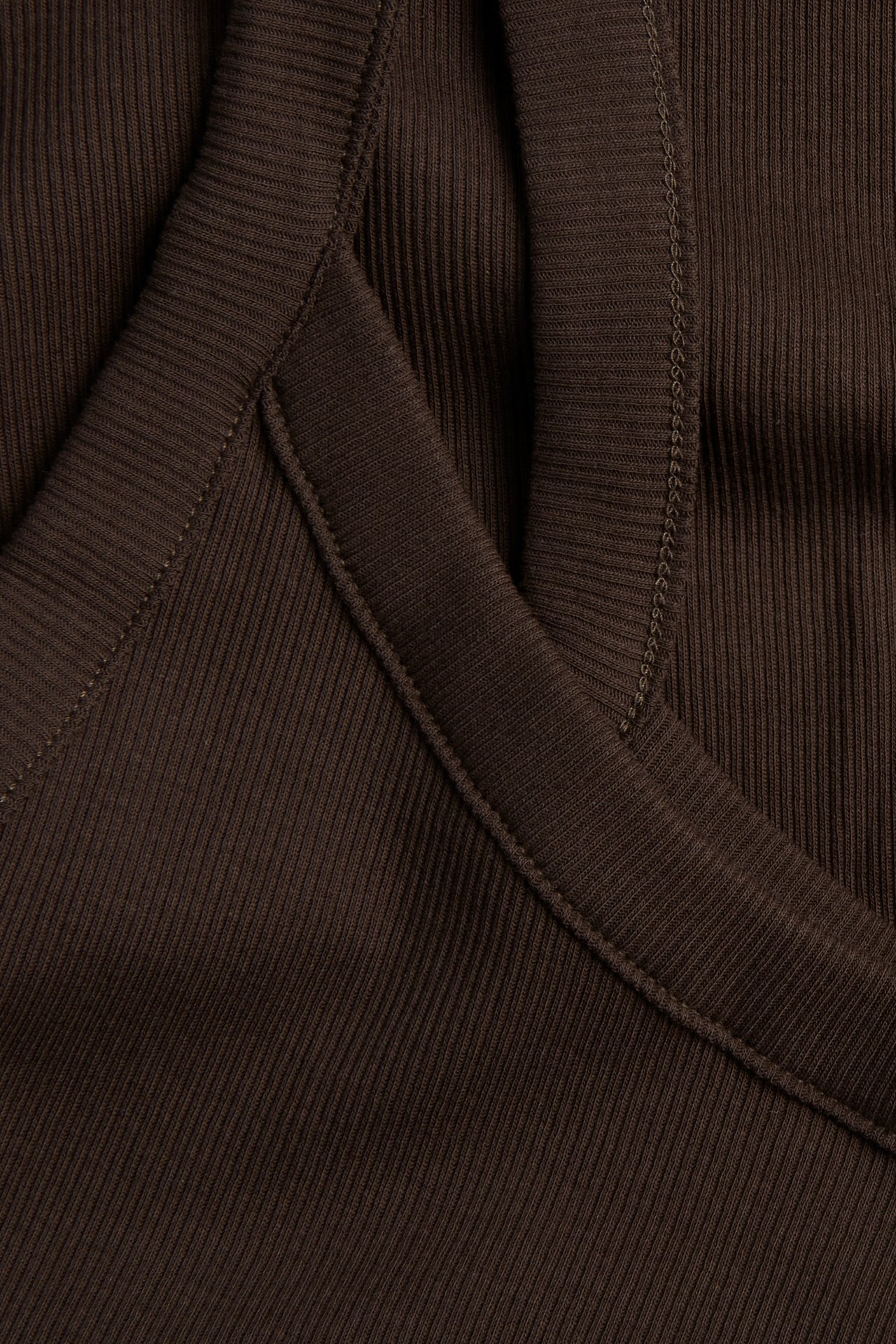 Nærbilde av en mørkebrun ribbet singlet, som viser stoffteksturen og smale stropper.
