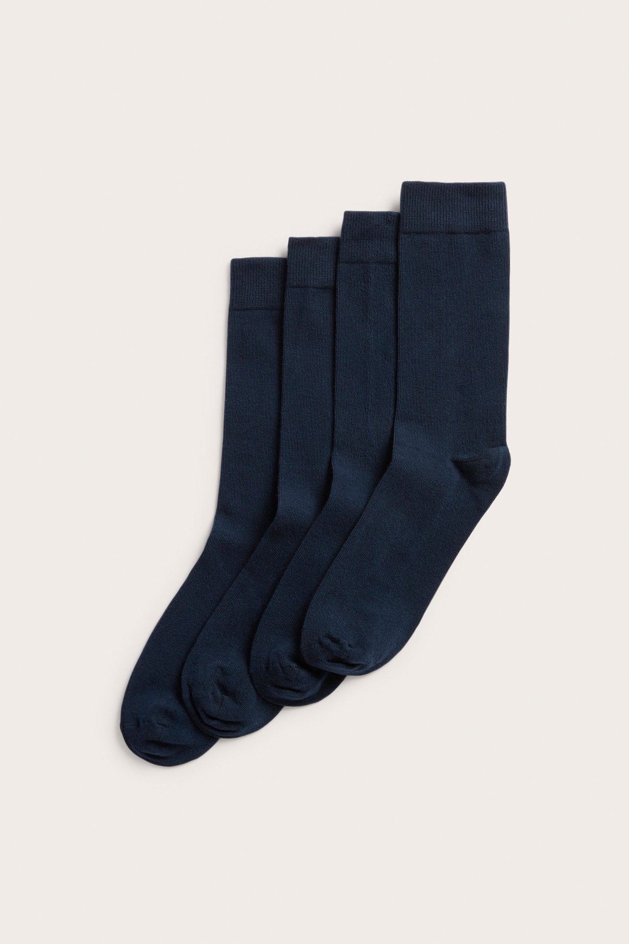 Framsidan av fyra mörkblå enfärgade slätstickade herrstrumpor med mjuk resårkant.