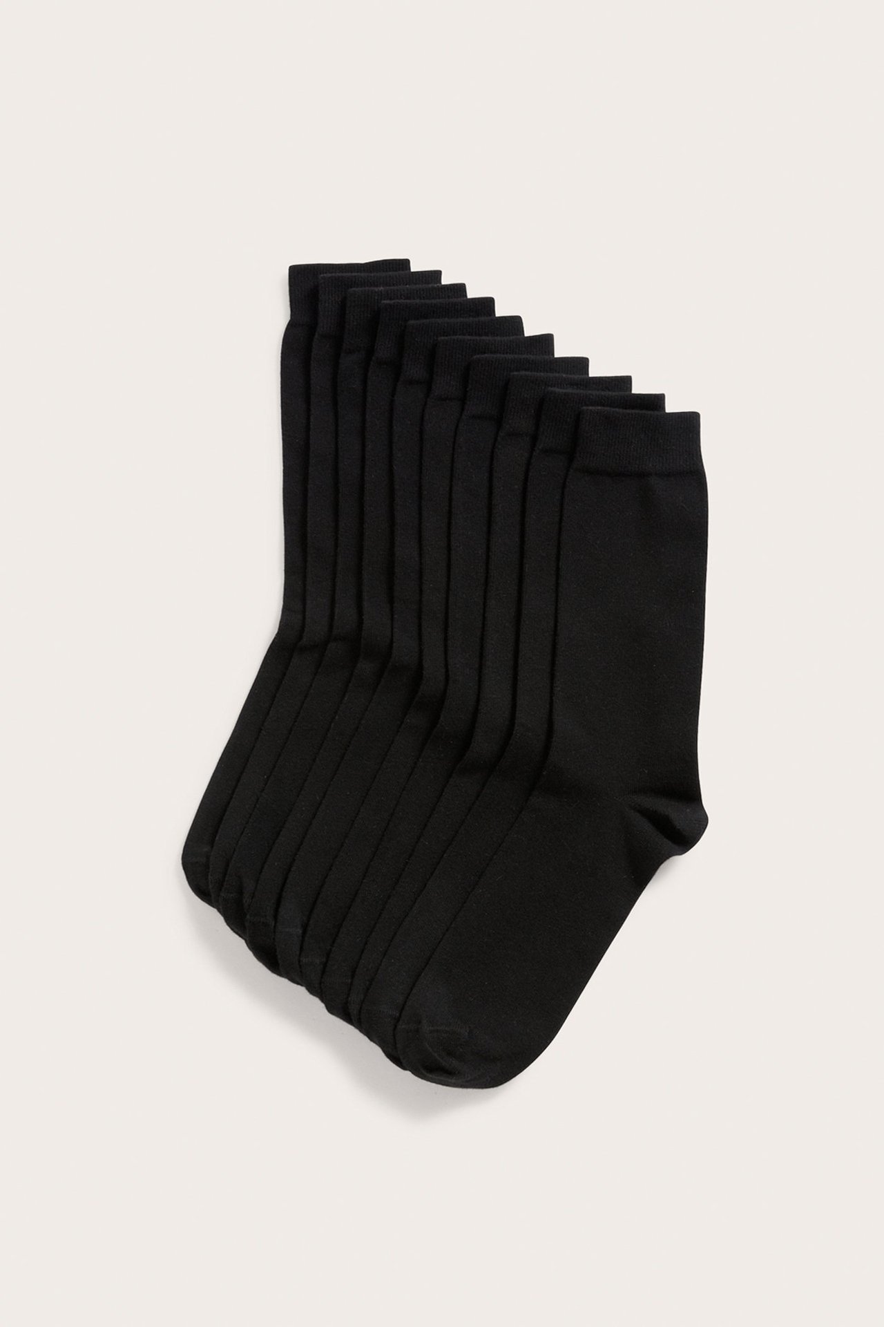 Hög vinkelvy av tio par svarta enfärgade crewstrumpor i bomullsblandning, utspridda.