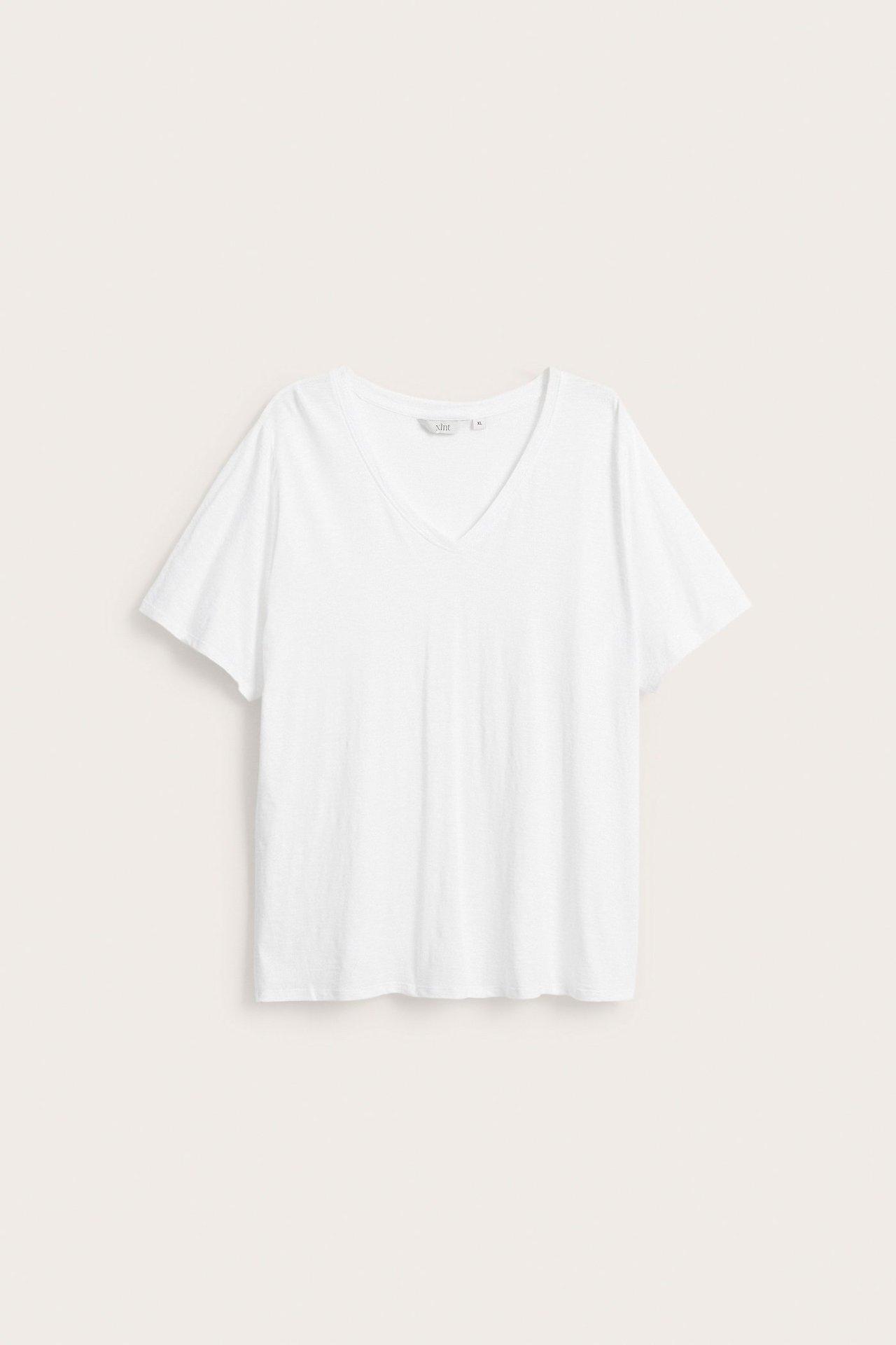 Edestä näkymä valkoisesta V-aukkoisesta puuvillaisesta T-paidasta, jossa on lyhyet hihat.
