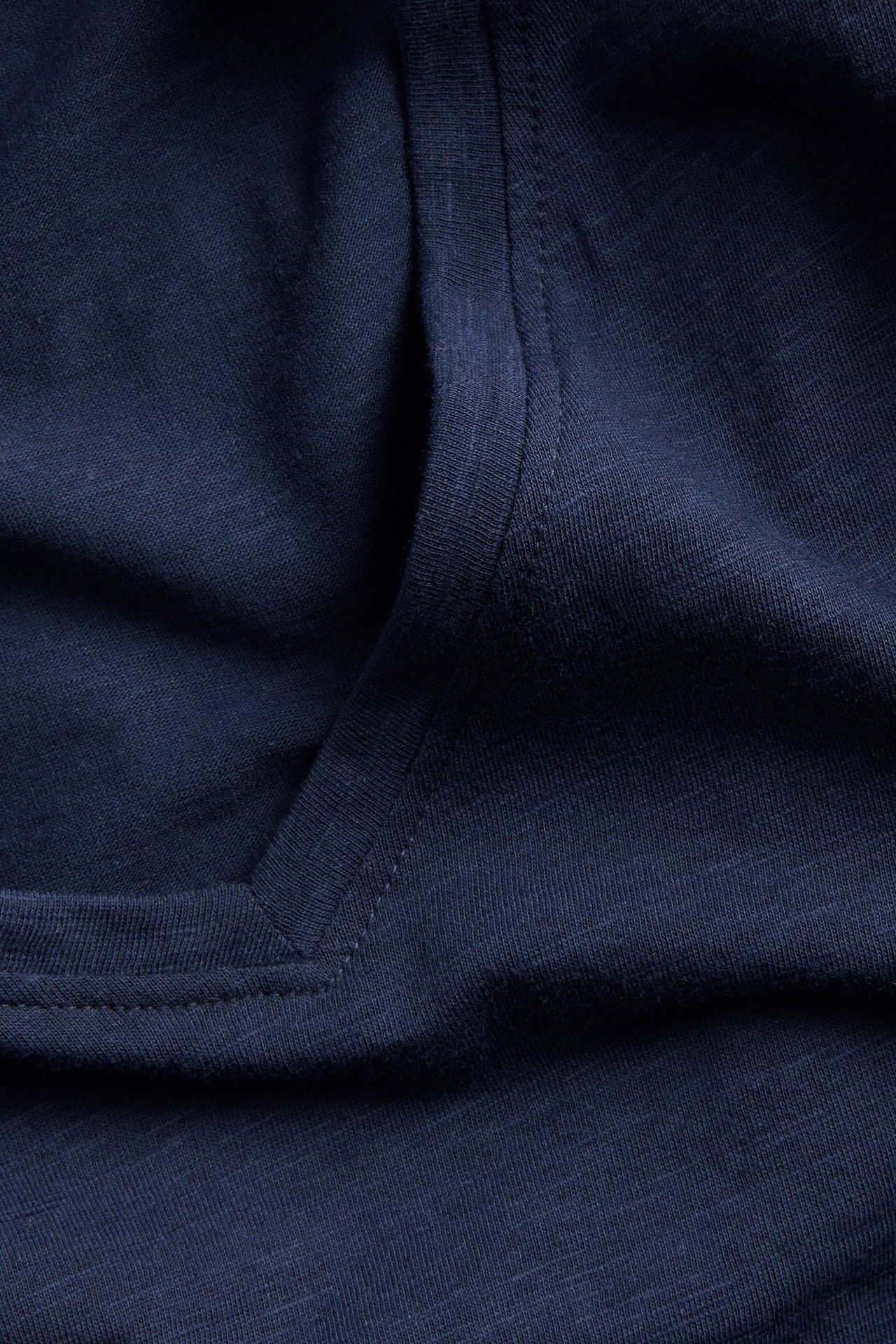 Nærbilde av en mørkeblå V-hals t-skjorte i bomull.