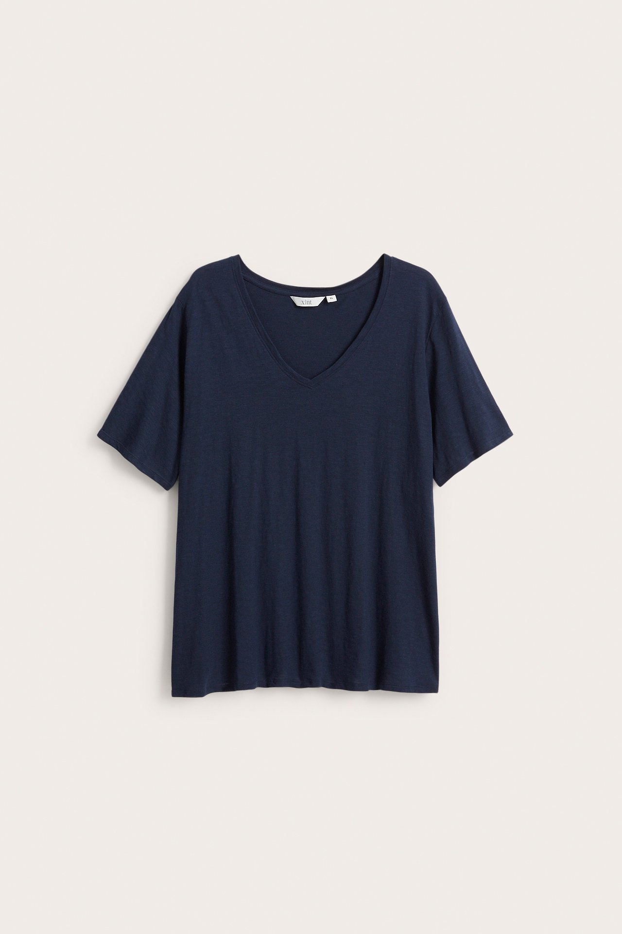 Forfra: en mørkeblå, løs, kortermet V-hals t-skjorte i bomull.