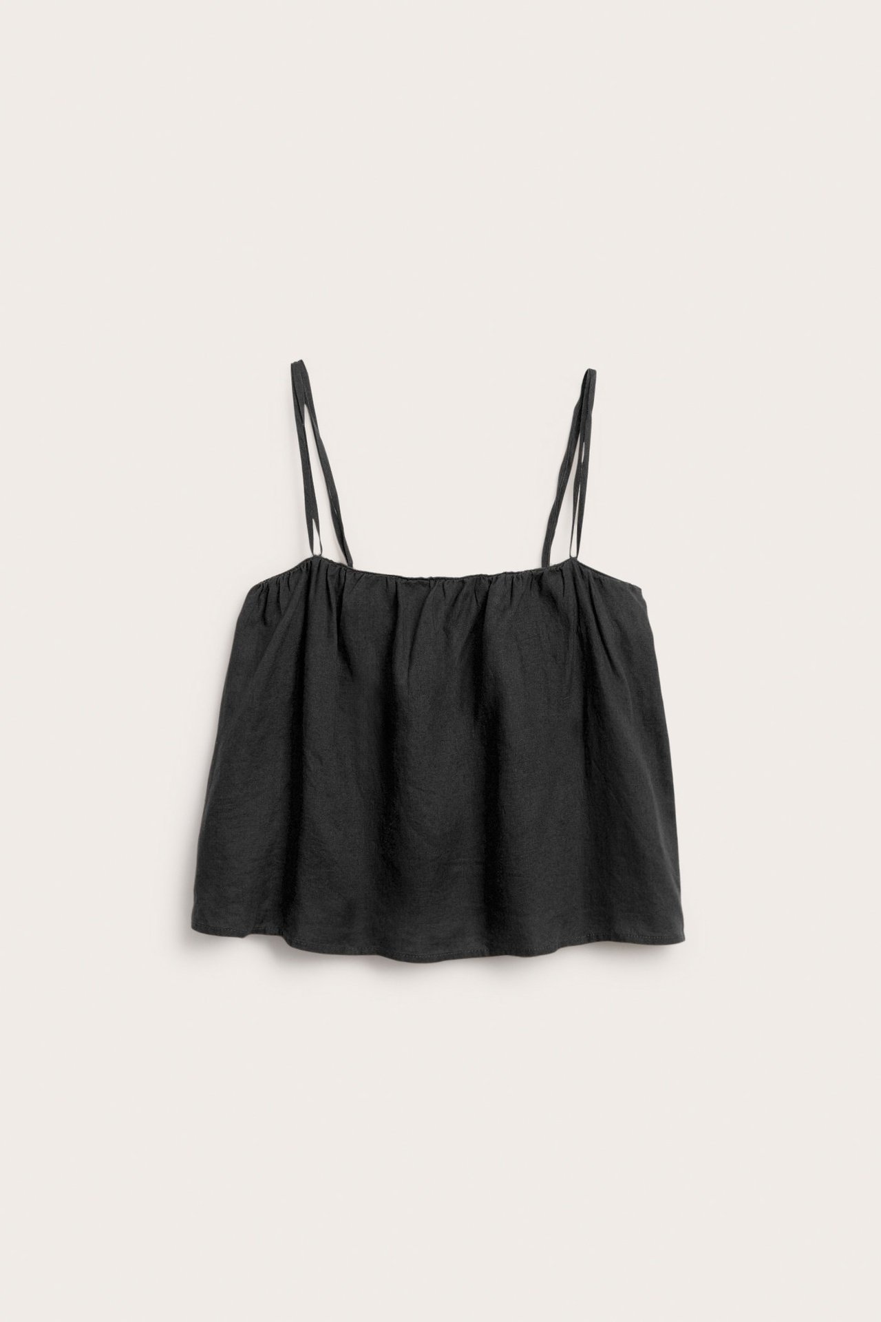 Frontvy av ett svart linne i linne med smala axelband och rynkad halslinning.