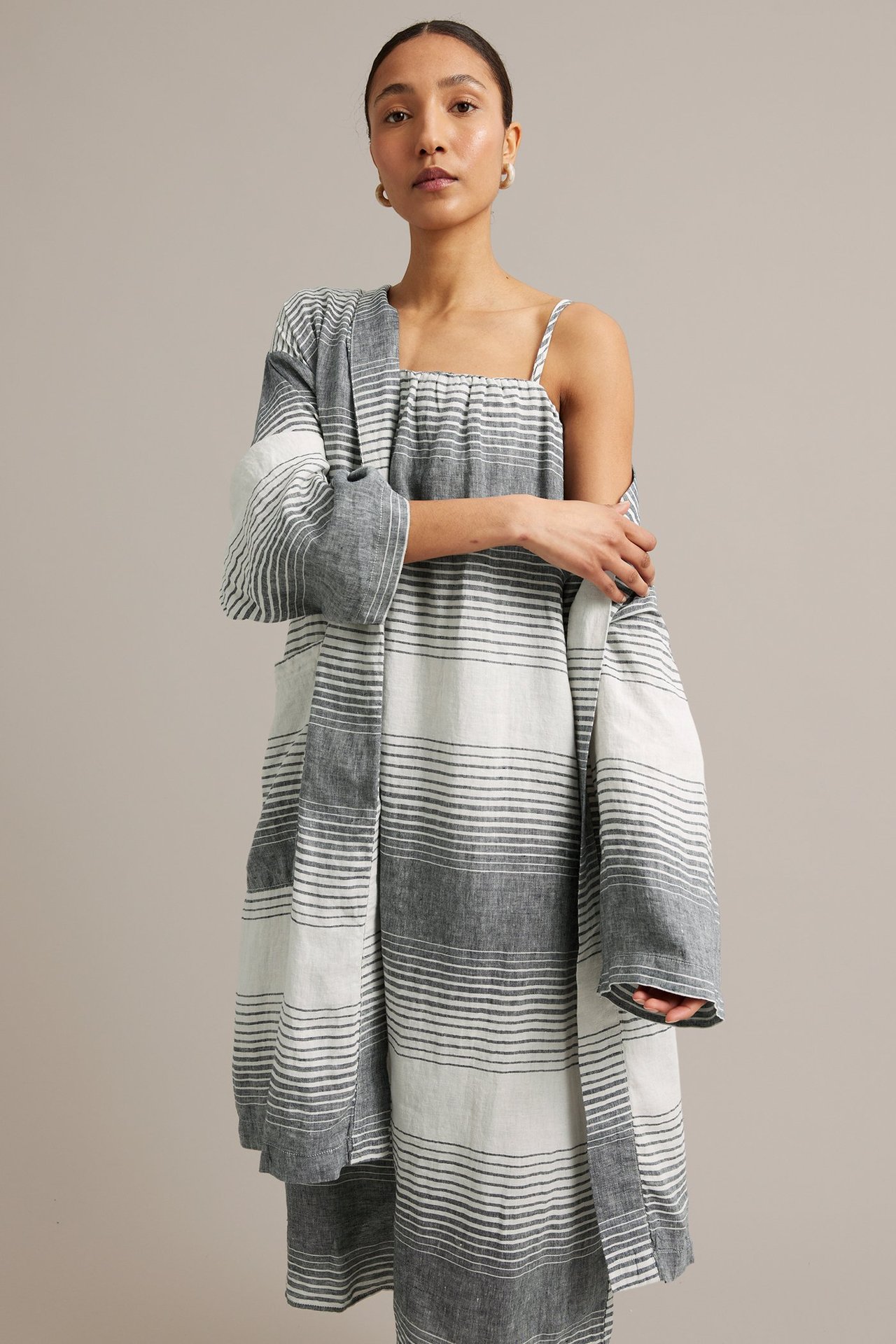 Forfra: kvinne i mørkeblåstripet linseletoppkjole med tynne stropper og matchende lang cardigan.