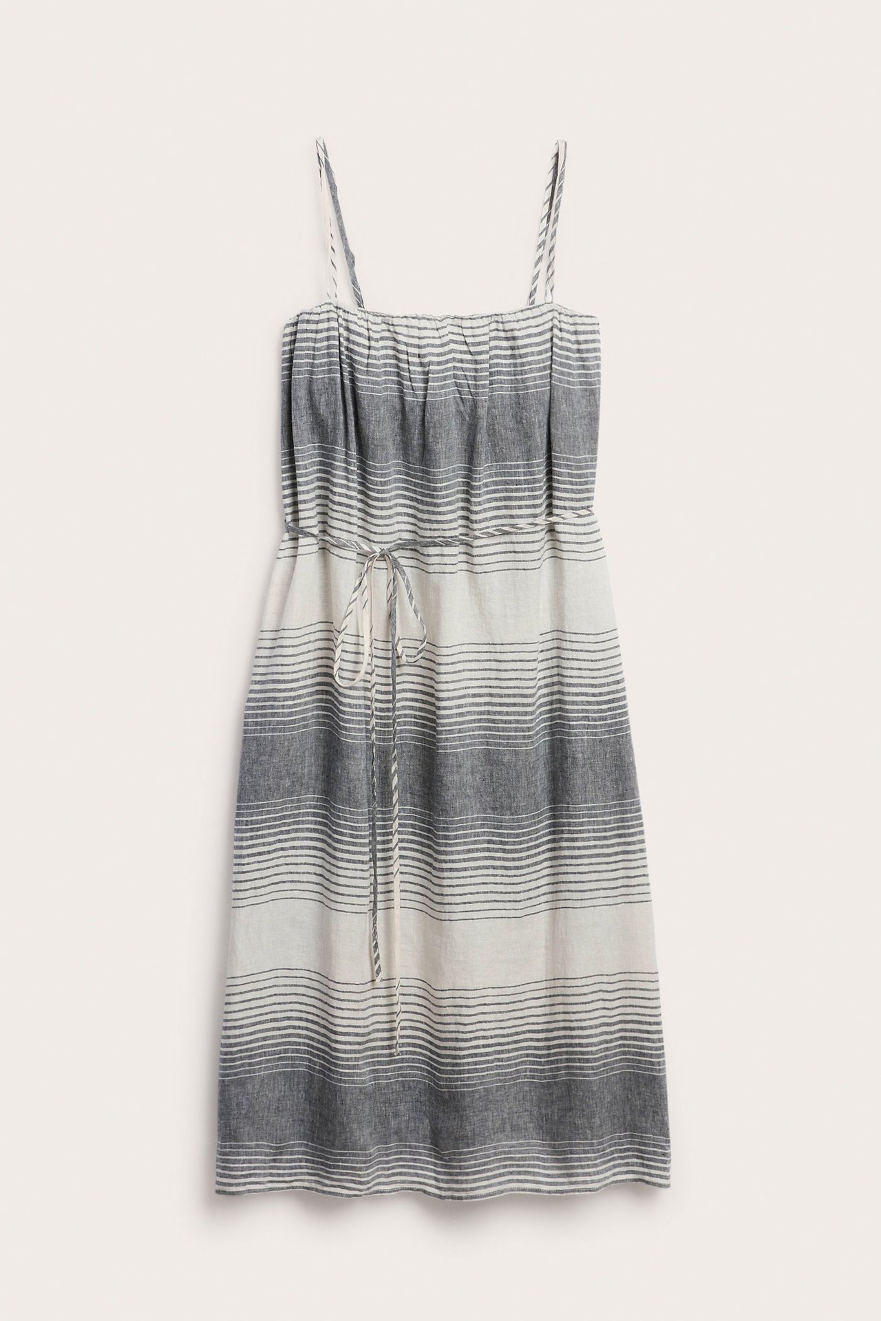 Framifrån, randig linneklänning i mörkblått och benvitt med smala axelband och knytskärp.