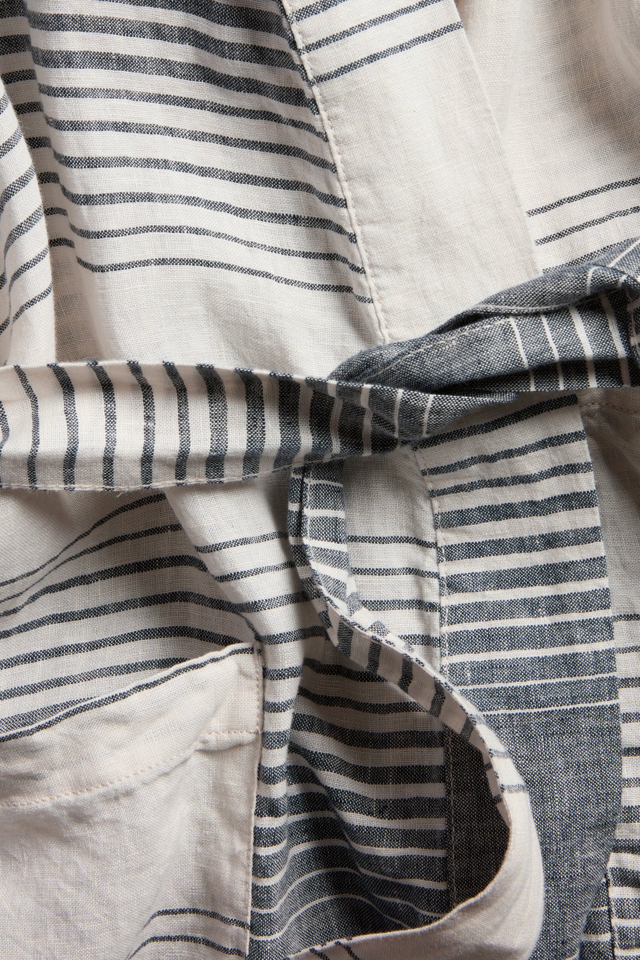 Zbliżenie na pasiastą lnianą kimonę z ciemnoniebieskim i jasnym wzorem, wiązanym paskiem i kieszenią.