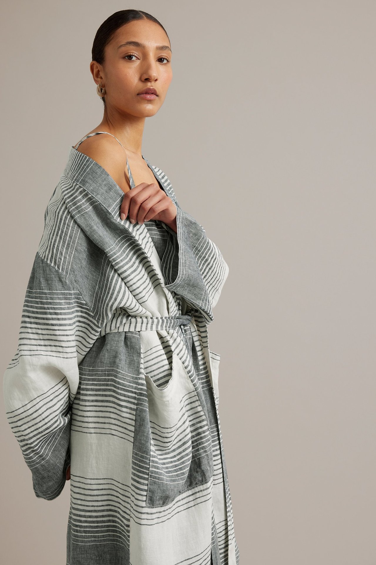 Kvinne i mørkblå, hvitstripet lin-kimono med knytebelte, over en matchende topp.