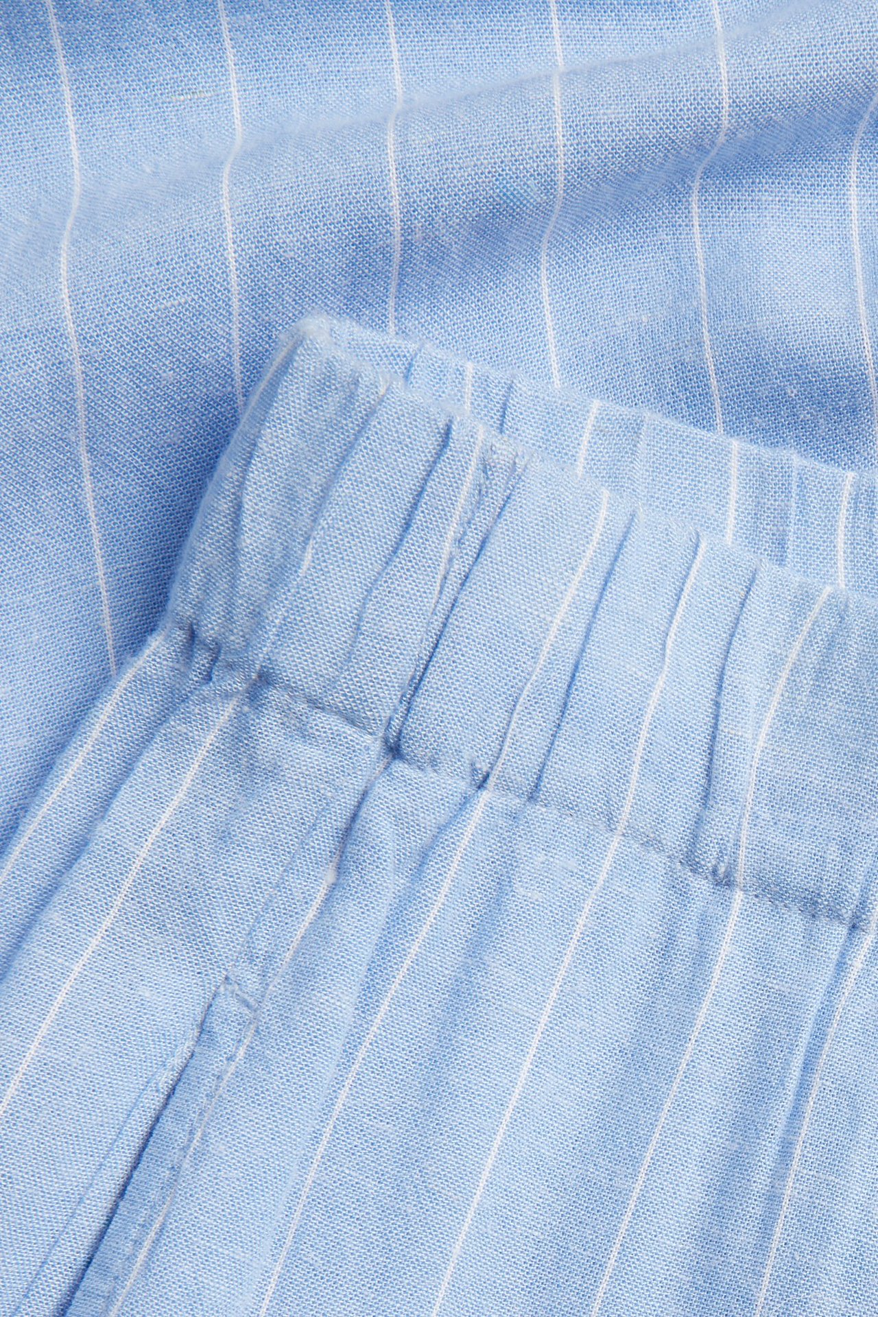 Zbliżenie na szerokie, jasnoniebieskie spodnie w paski z wiskozy i lnu z elastycznym pasem.