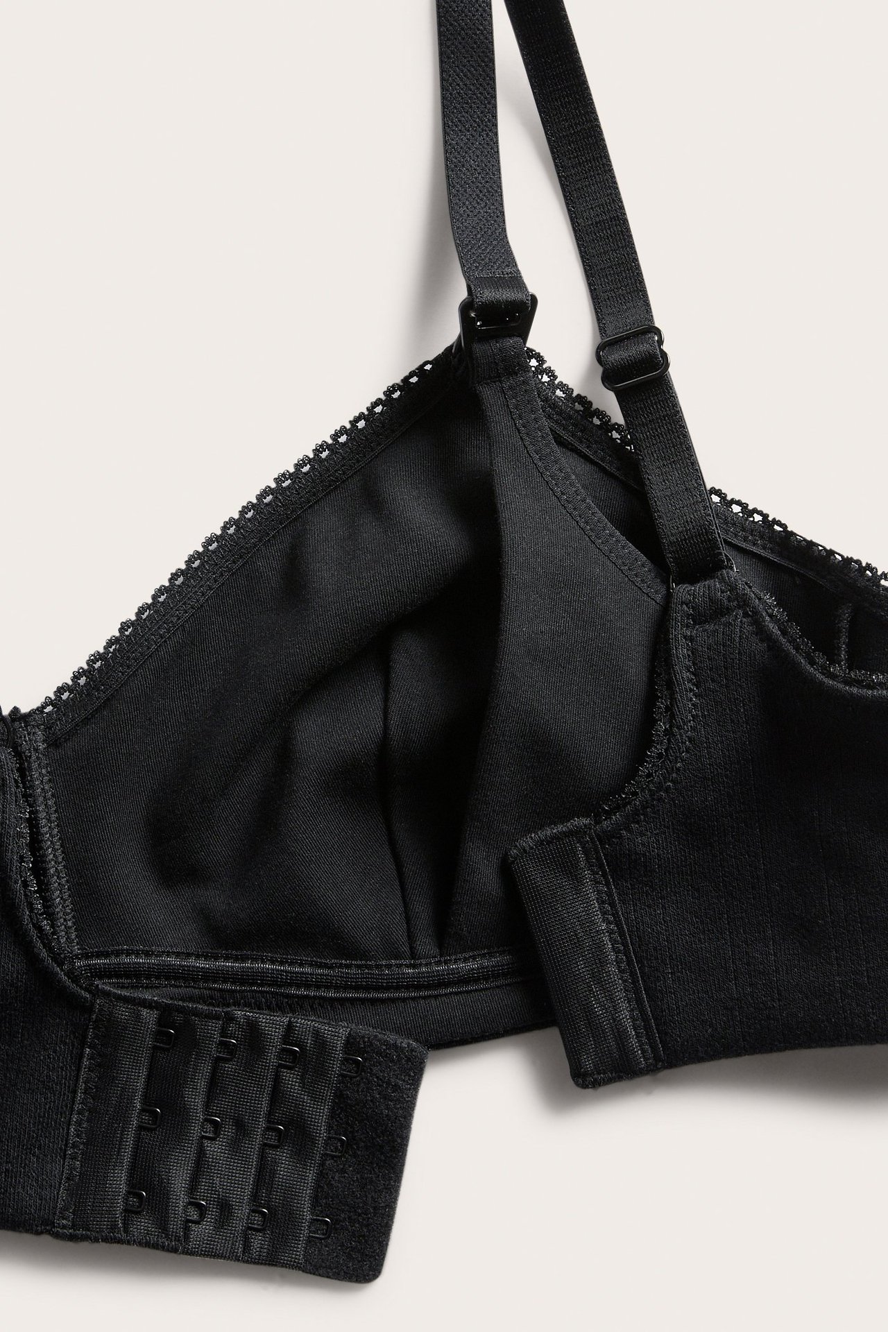 Lähikuva mustasta pointelle-rintaliivistä: toppamattomat kupit, säädettävät olkaimet, hakaskiinnitys.