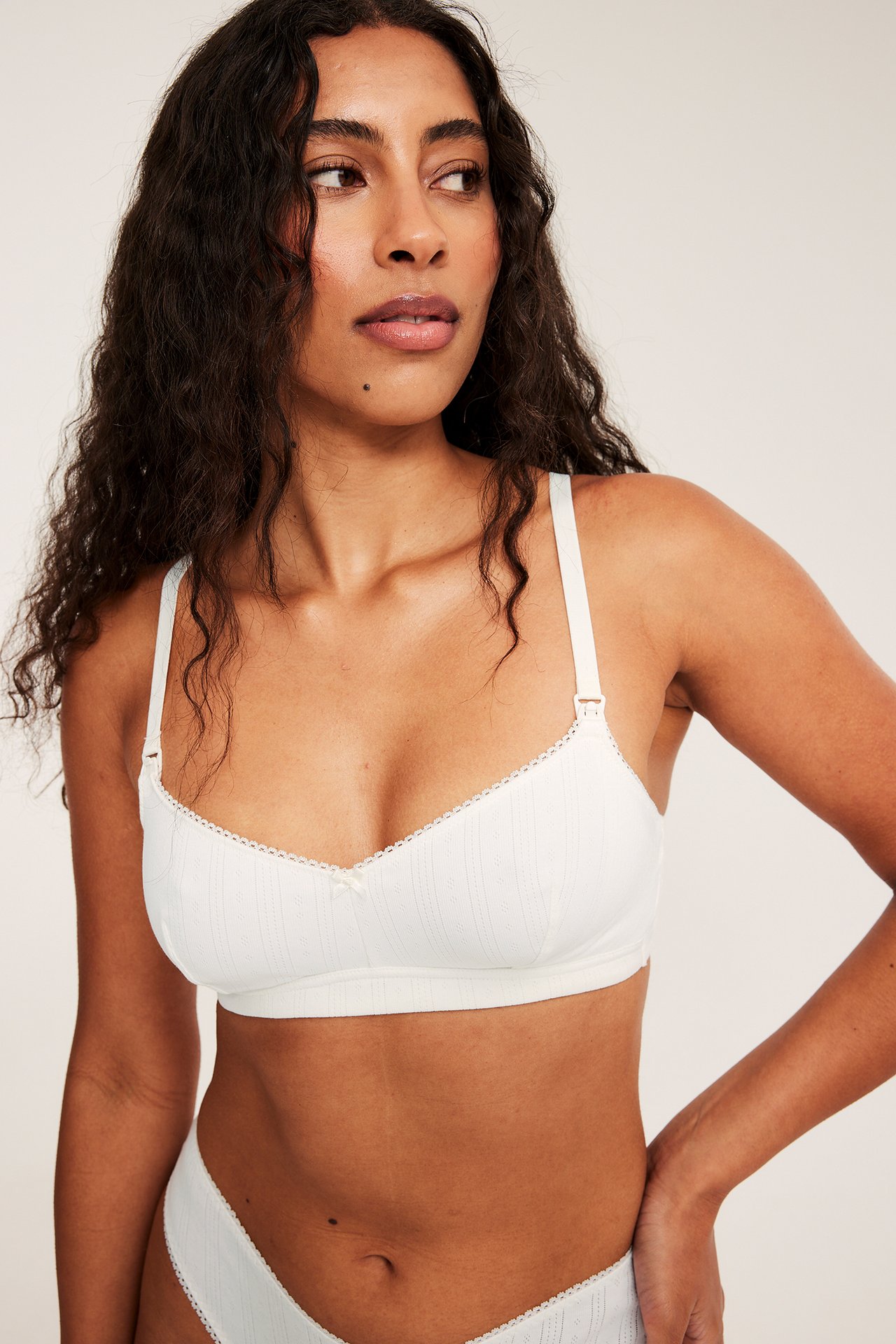 Framifrån en kvinna i offwhite amnings-bh i pointelle-ribb med matchande trosor.