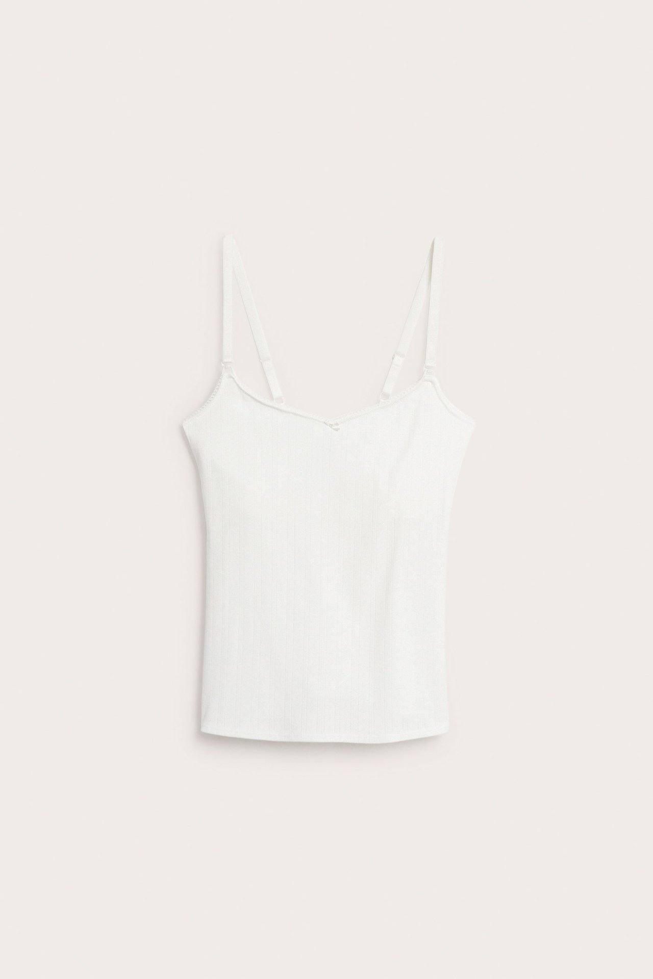 Edestäpäin: Luonnonvalkoinen pointelle-ribbi imetystoppi säädettävillä olkaimilla ja soljilla.