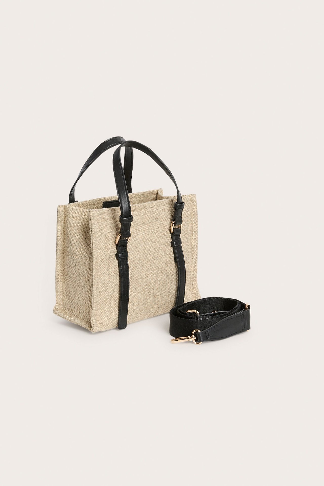 Etunäkymä beigestä kangaskassista, mustilla kahvoilla ja irrotetulla säädettävällä olkahihnalla.