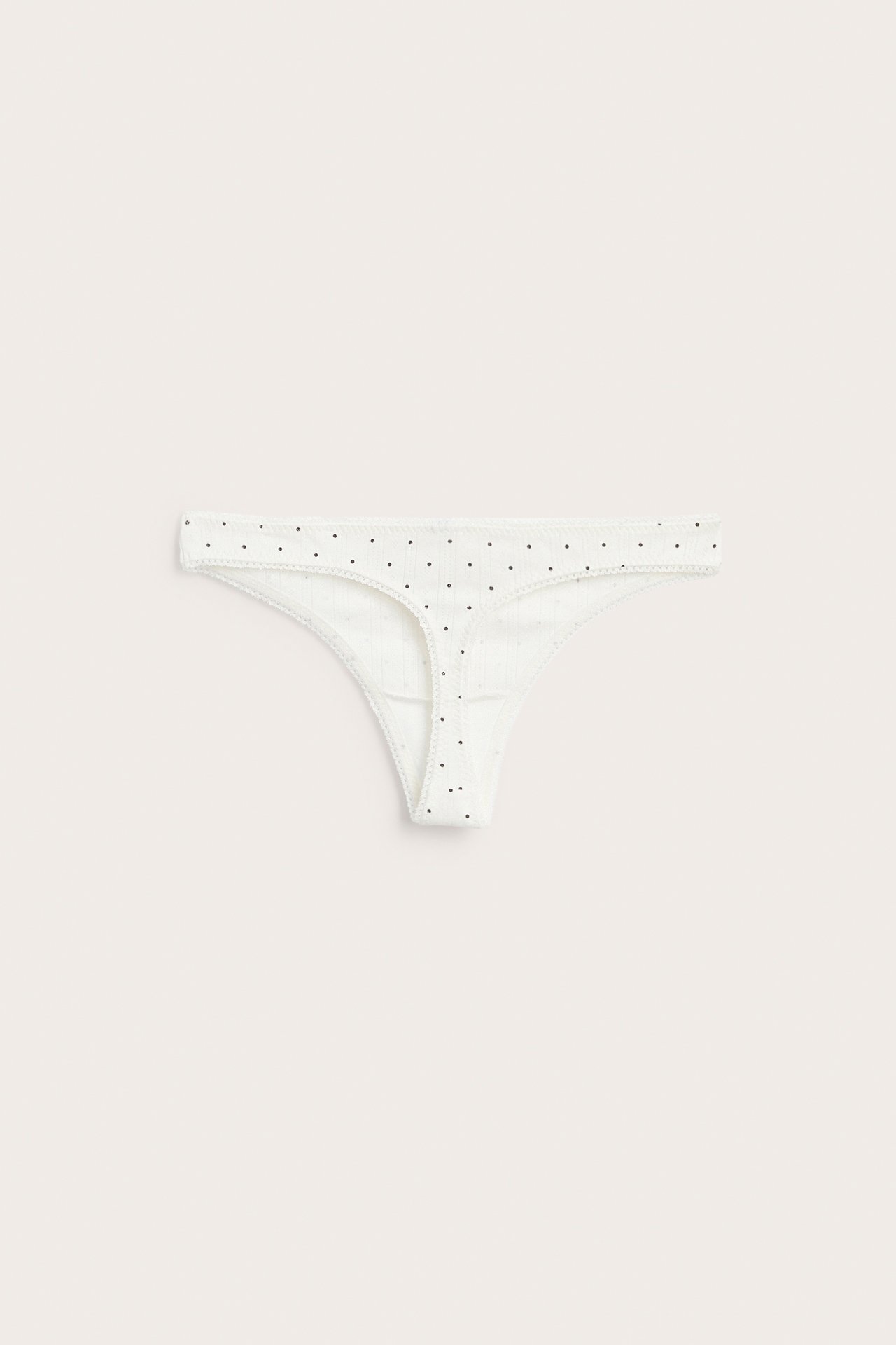 Forfra, offwhite pointelle stringtruse med små svarte prikker.