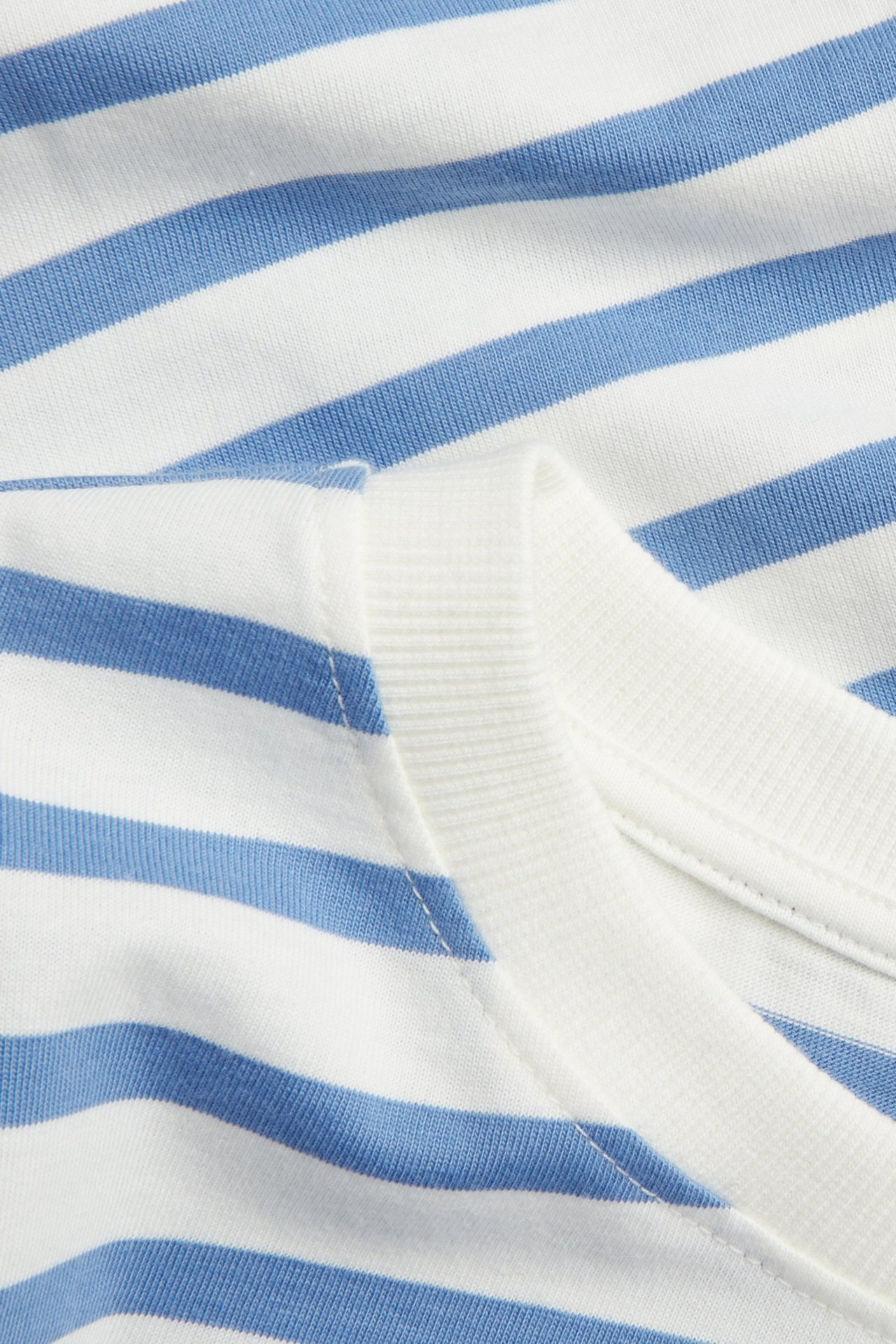 Lähikuva sinivalkoraidallisesta puuvillaisesta t-paidasta, jossa resori pääntie.