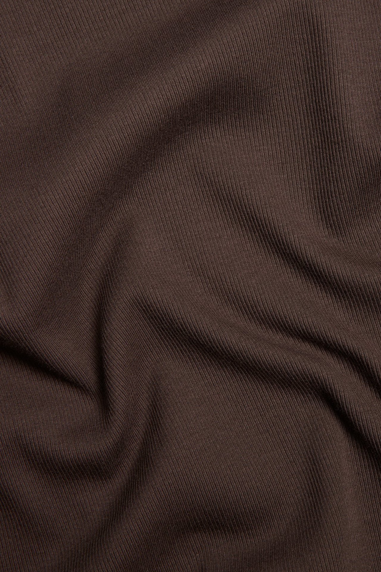 Zbliżenie ciemnobrązowej, prążkowanej tkaniny bluzki z długim rękawem, z widoczną fakturą.