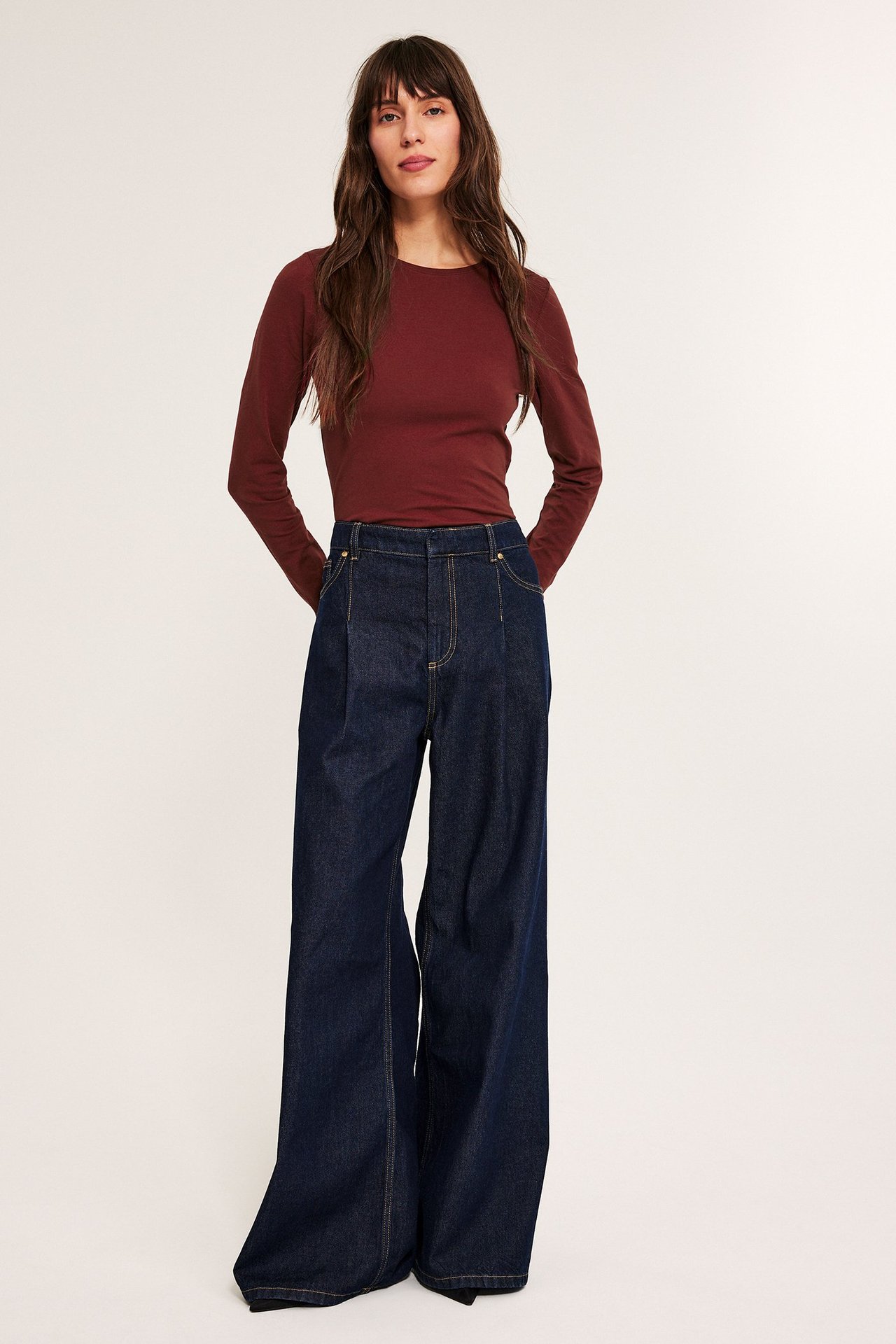 Kvinne bruker en rød langermet topp med rund hals, tettsittende og enkel.