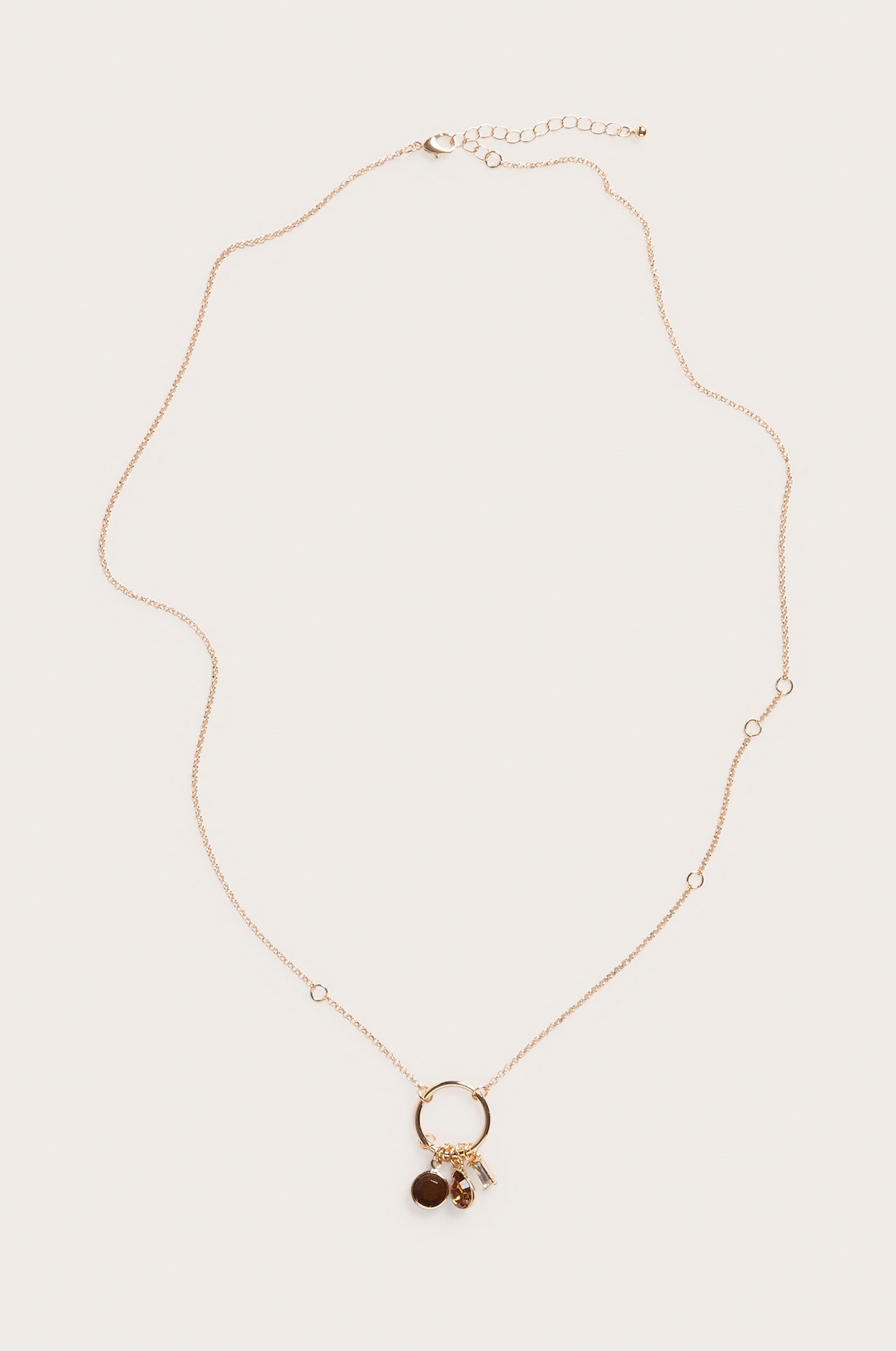 Full frontvisning av et gullfarget kjedehalsbånd med en sentral ring som holder tre brune og klare anheng.