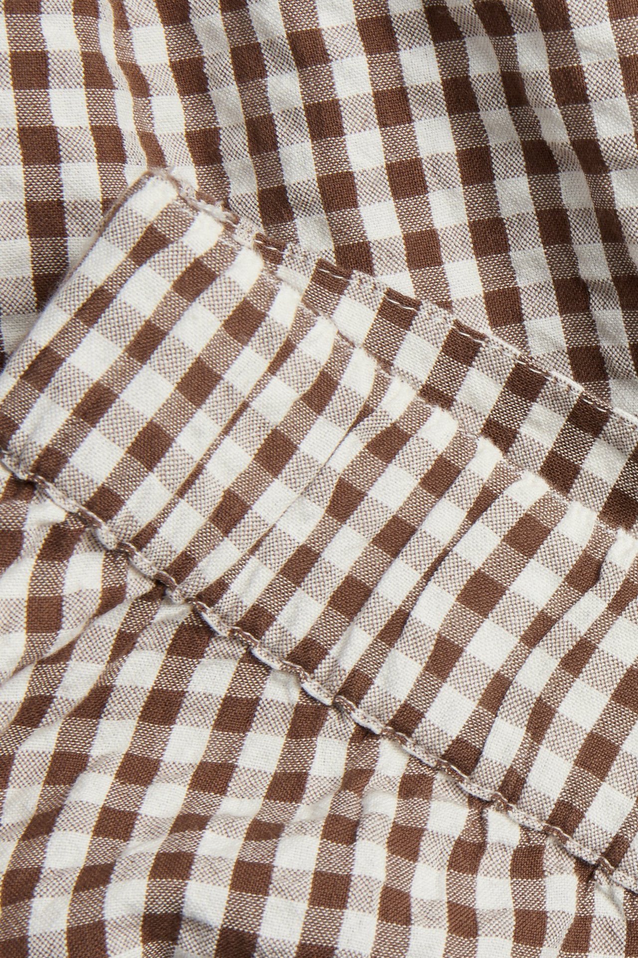 Zbliżenie na brązowo-białą spódnicę z seersuckera w kratę, z marszczonym szwem.