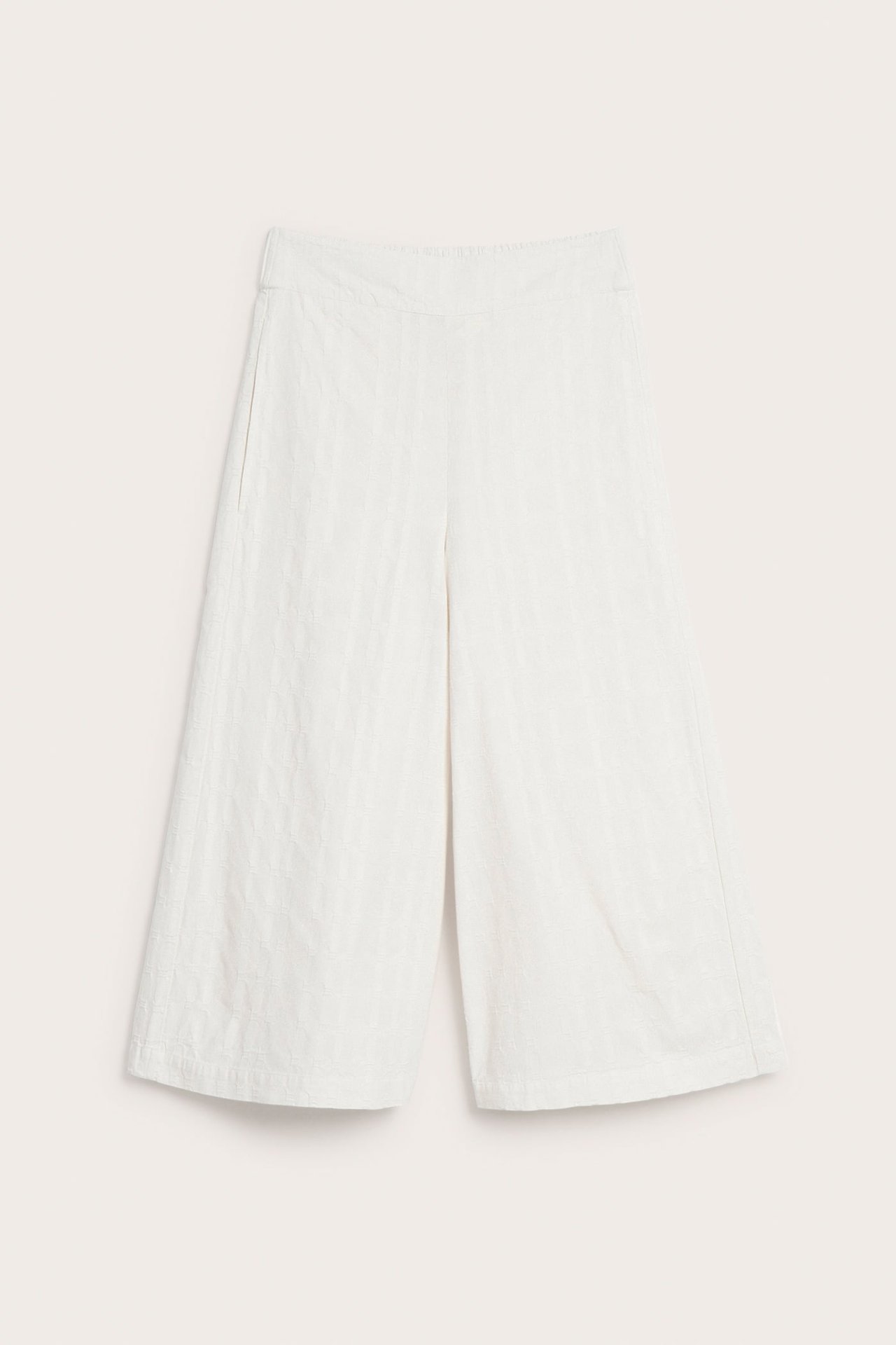 Edestäpäin valkoiset puuvillaiset pull-on culotte-housut, joissa hienostunut kuvio ja sivutaskut.