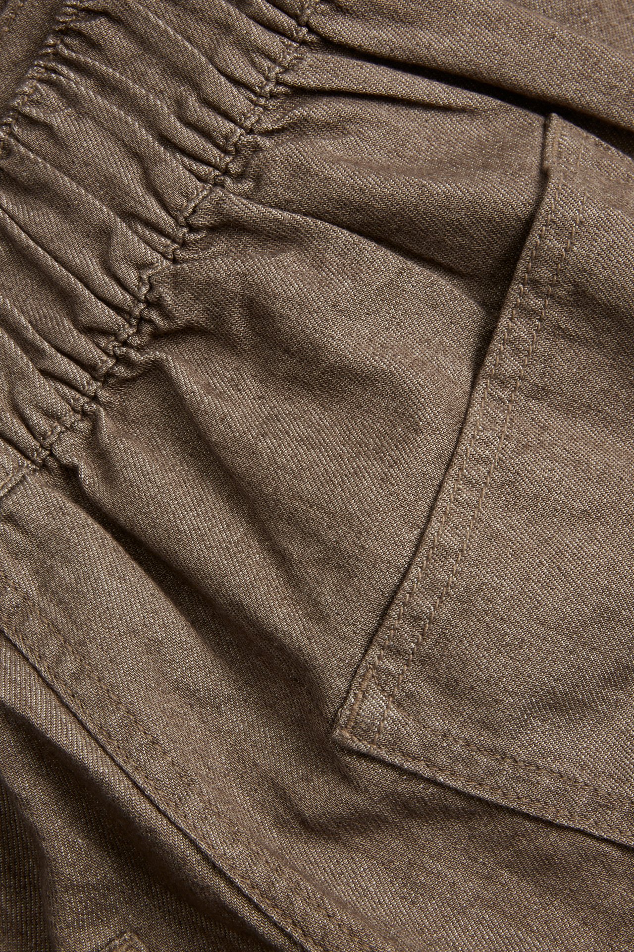 Nærbilde av brune bomulls pull-on culotte-jeans med strikk i midjen og sidelomme.