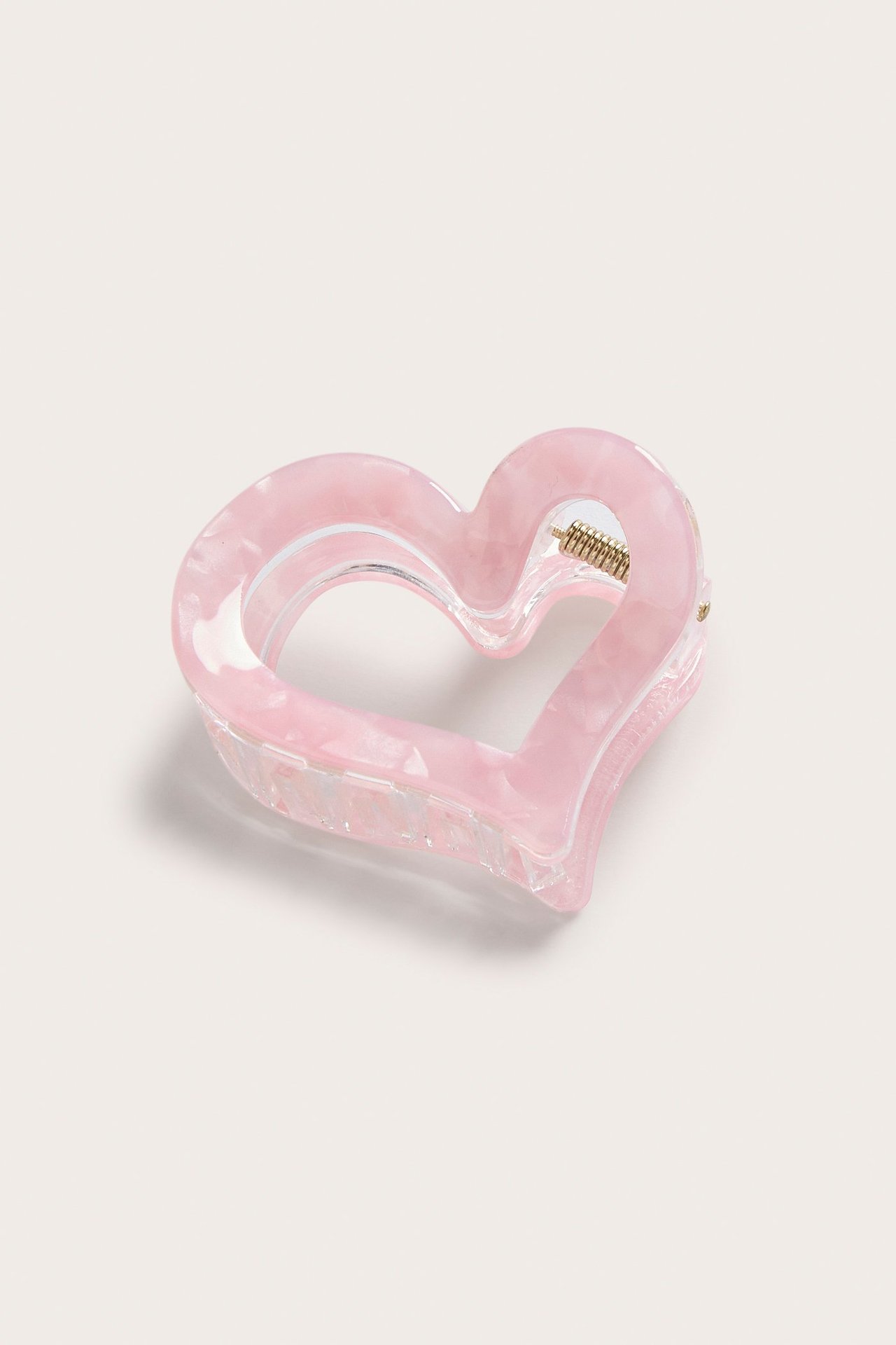 Lähikuva vaaleanpunaisesta, marmoroidusta sydänhiusklipsistä metallijousella.
