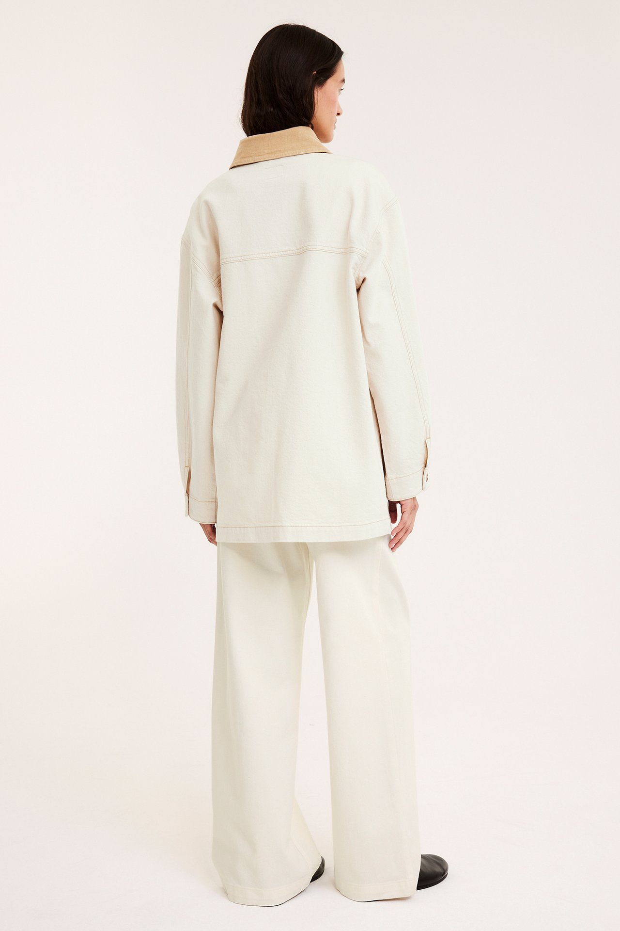 Widok z tyłu: Kobieta w beżowej kurtce twillowej z kołnierzem sztruksowym i szerokich spodniach.