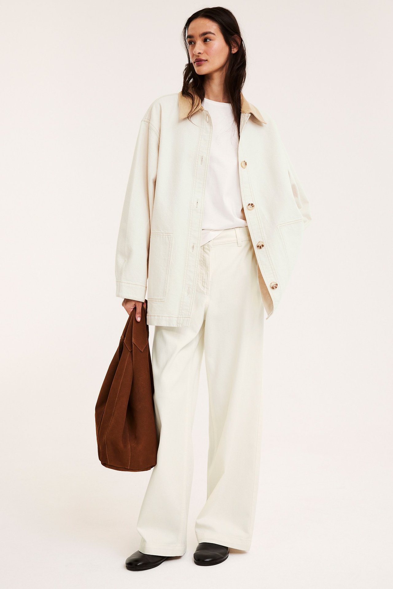 Widok z przodu, kobieta w beżowej kurtce twill, sztruksowy kołnierz, szerokie beżowe spodnie, z brązową torbą.