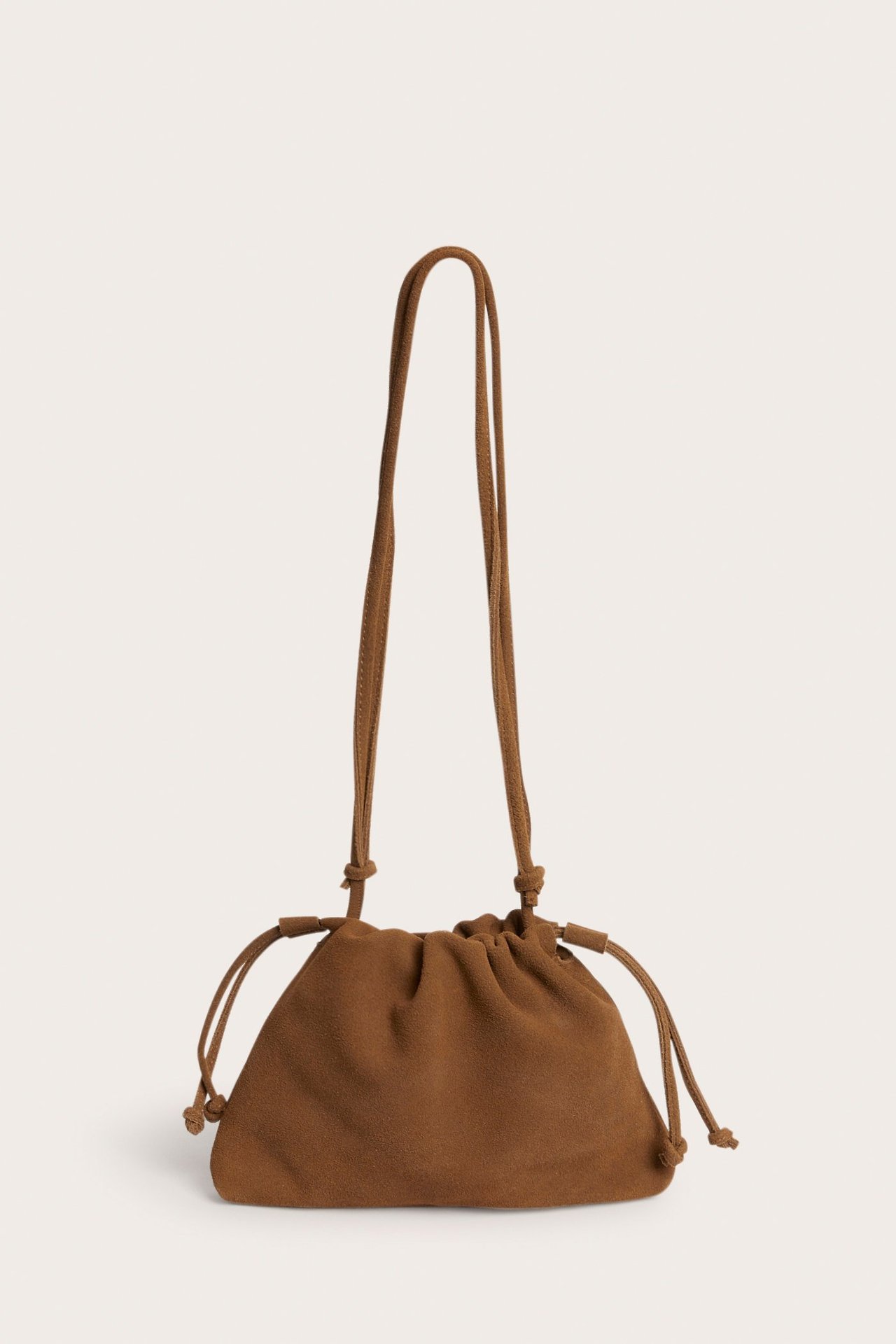 Widok z przodu jasnobrązowej zamszowej torebki ze ściągaczem i regulowanym paskiem.