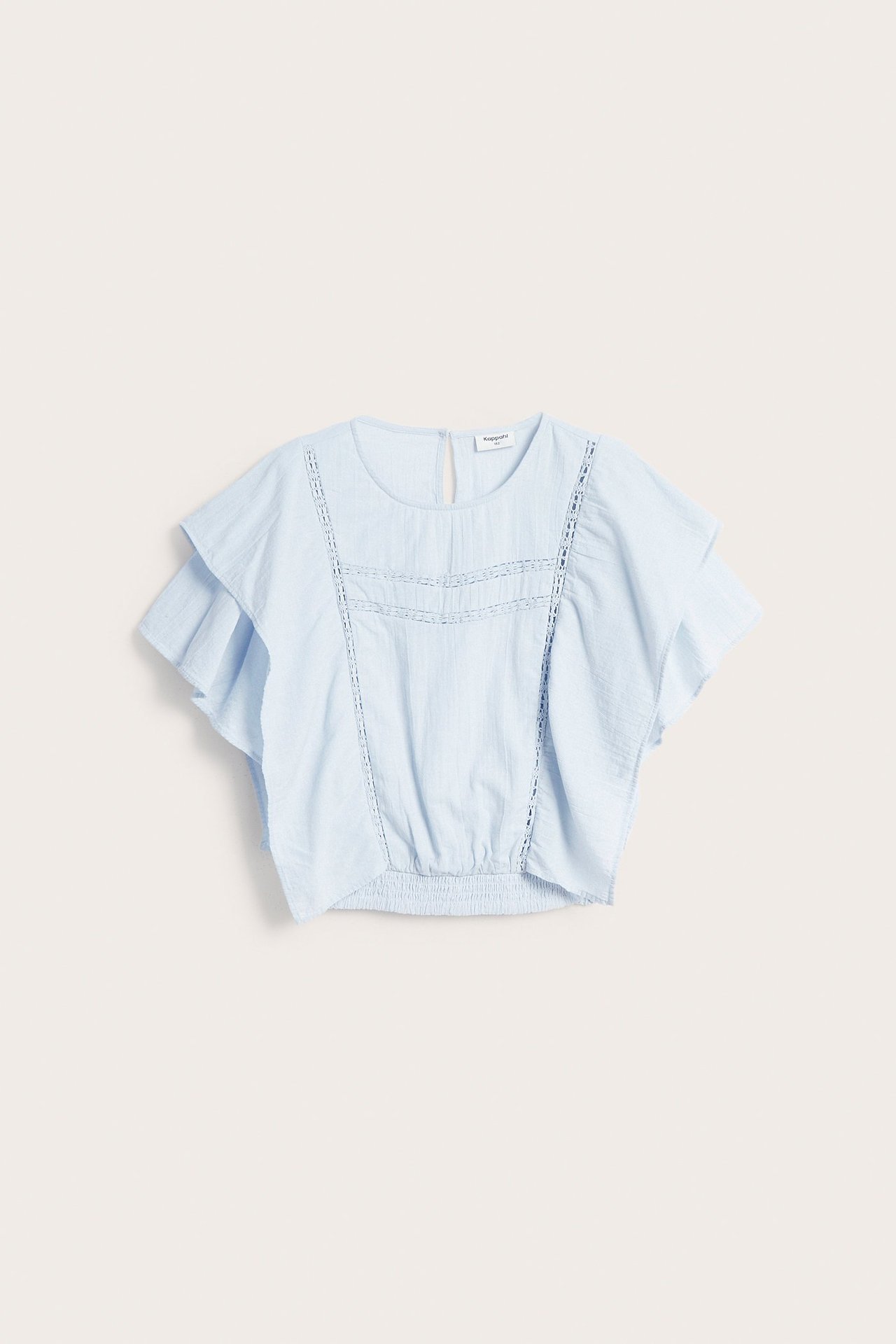 Framifrån, en ljusblå bomullsblus med batwingärmar, spetsdetaljer och smock i midjan.