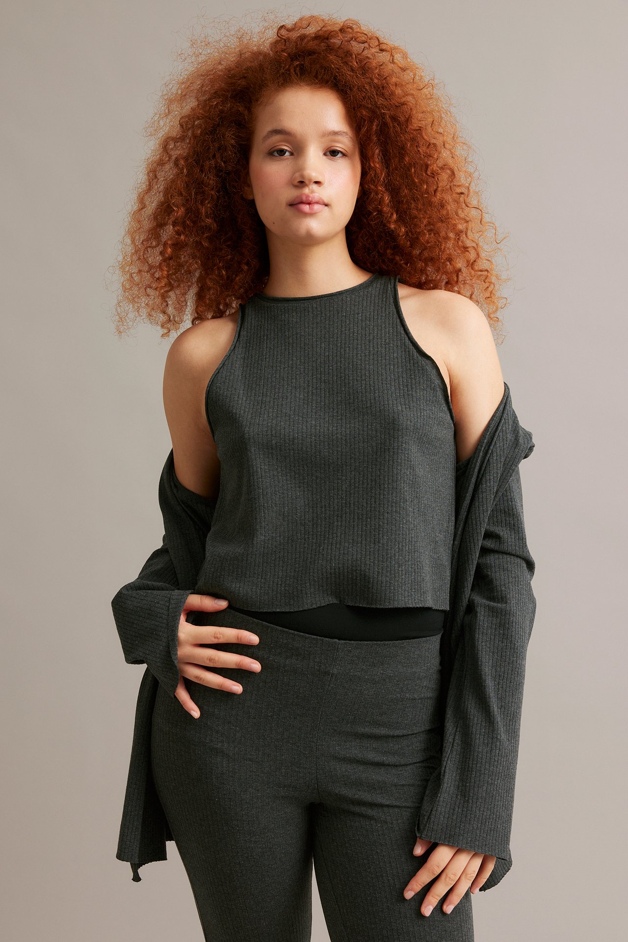 Frontbilde av kvinne i mørkegrå ribbet tanktopp, matchende åpen cardigan og bukser.