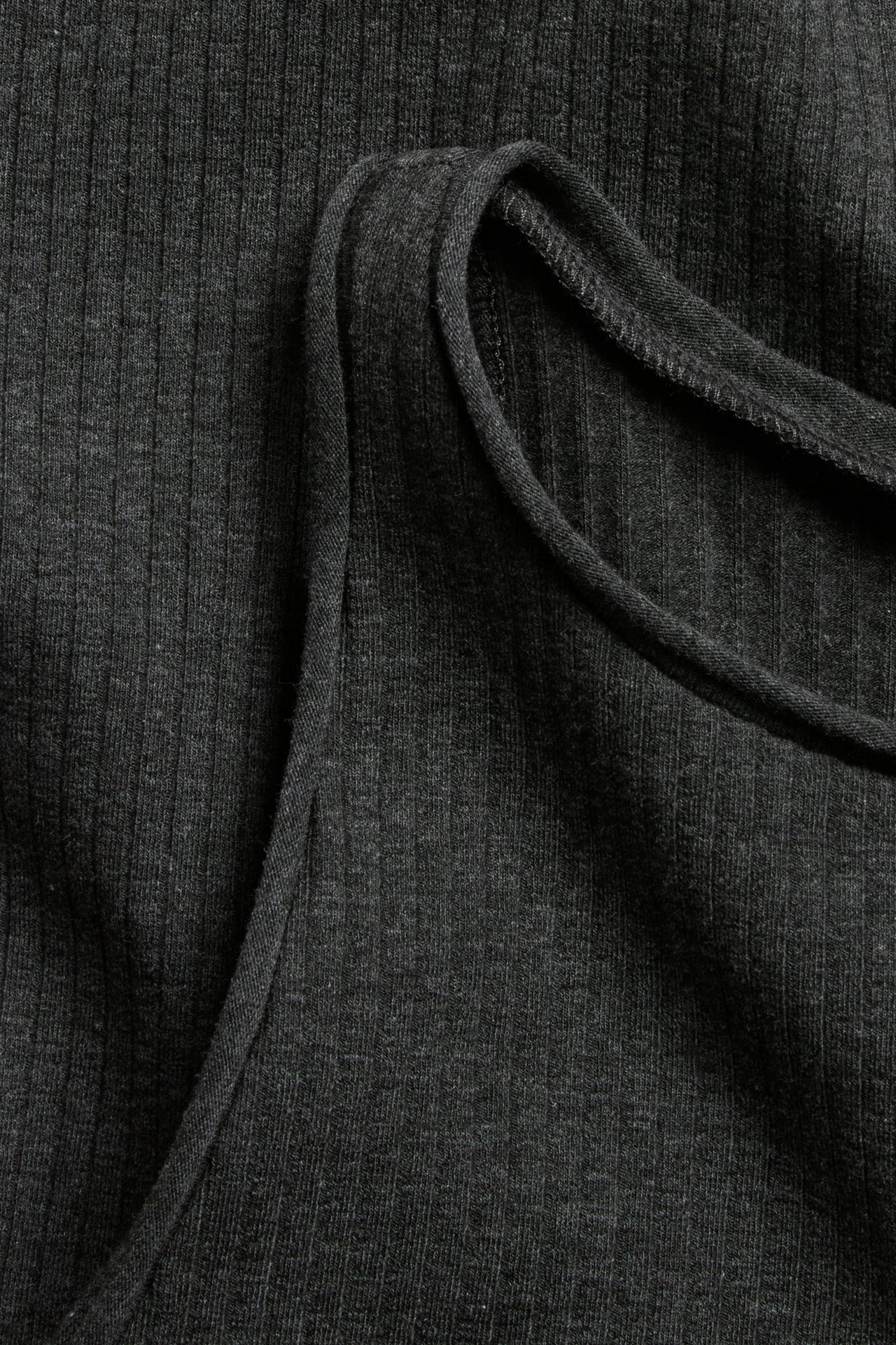 Zbliżenie antracytowego, melanżowego topu z prążkowanej dzianiny z surowymi wykończeniami brzegów.