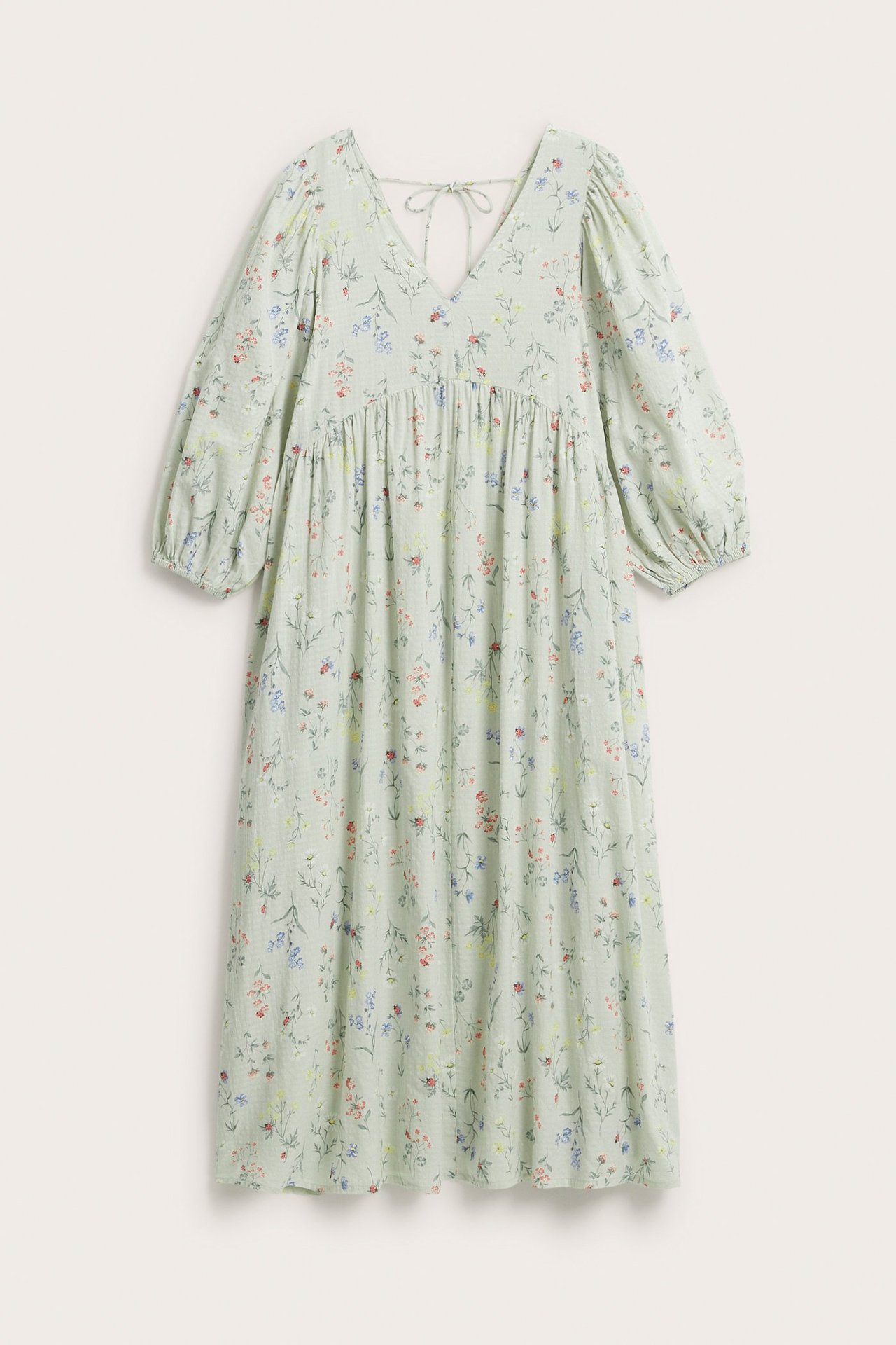 Frontvisning av lys grønn blomstret bomullskjole med V-hals, 3/4 puffermer og knytebånd bak.