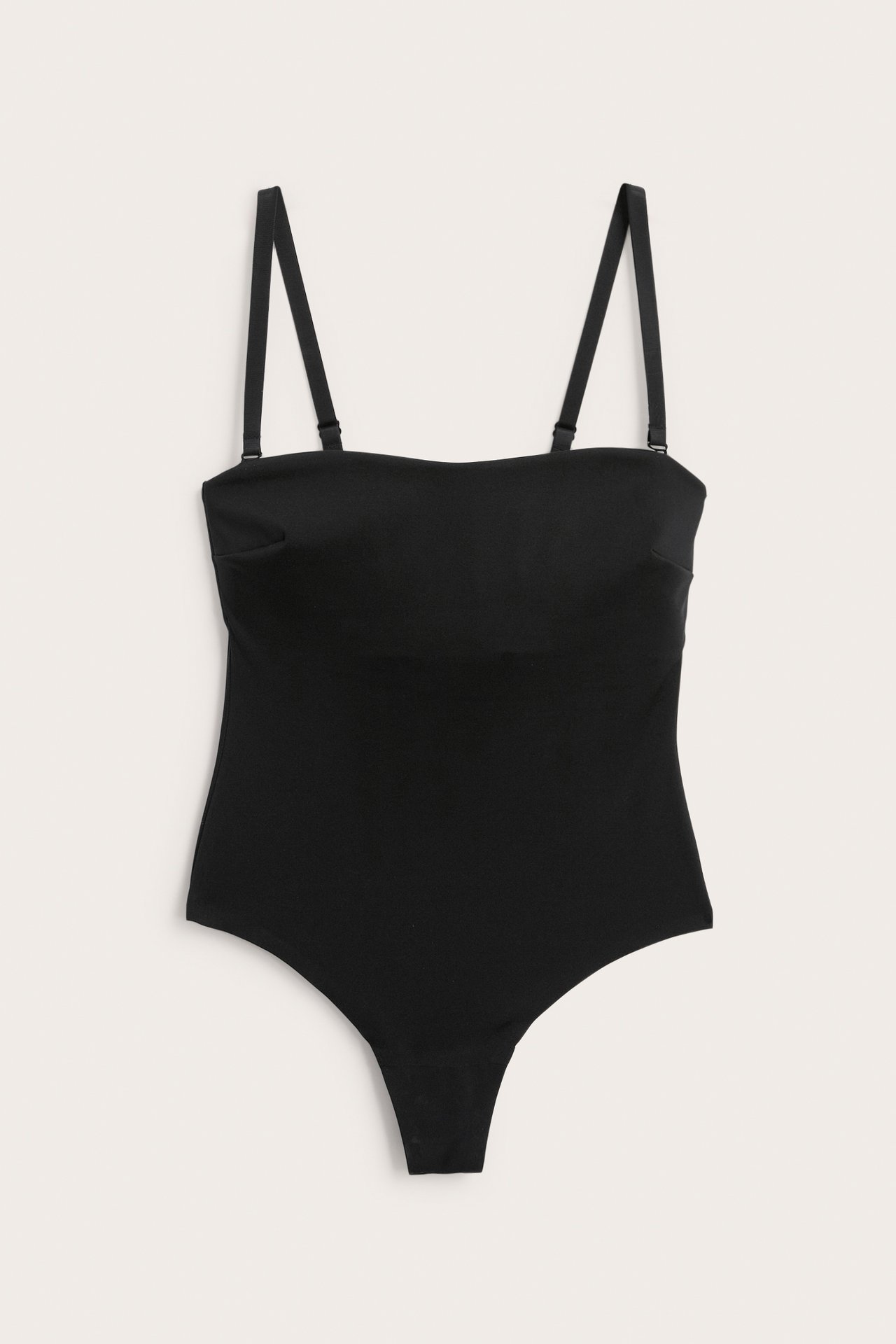 Framsida av svart vadderad mikro stringbody med avtagbara axelband.