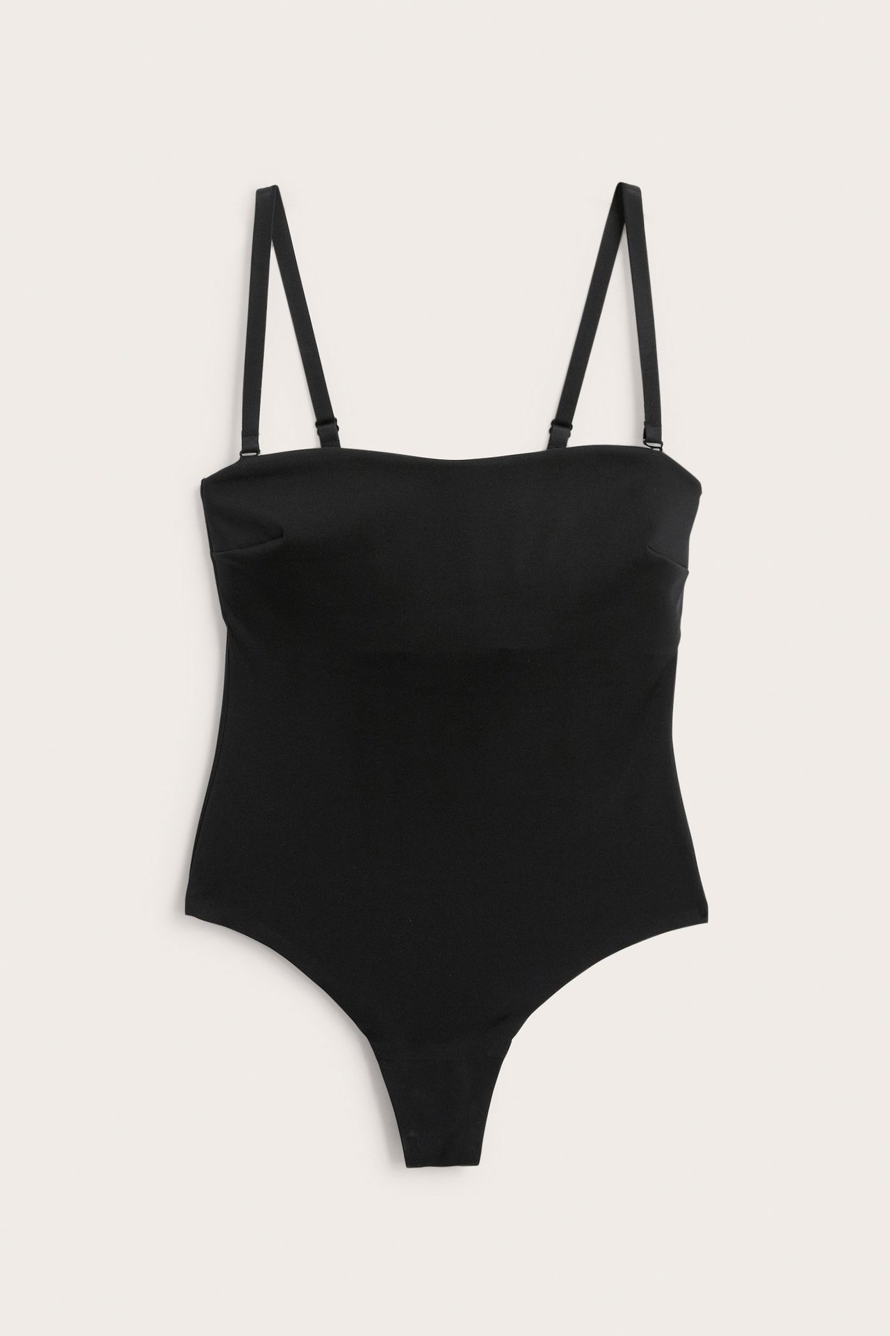 Framsida av svart vadderad mikro stringbody med avtagbara axelband.