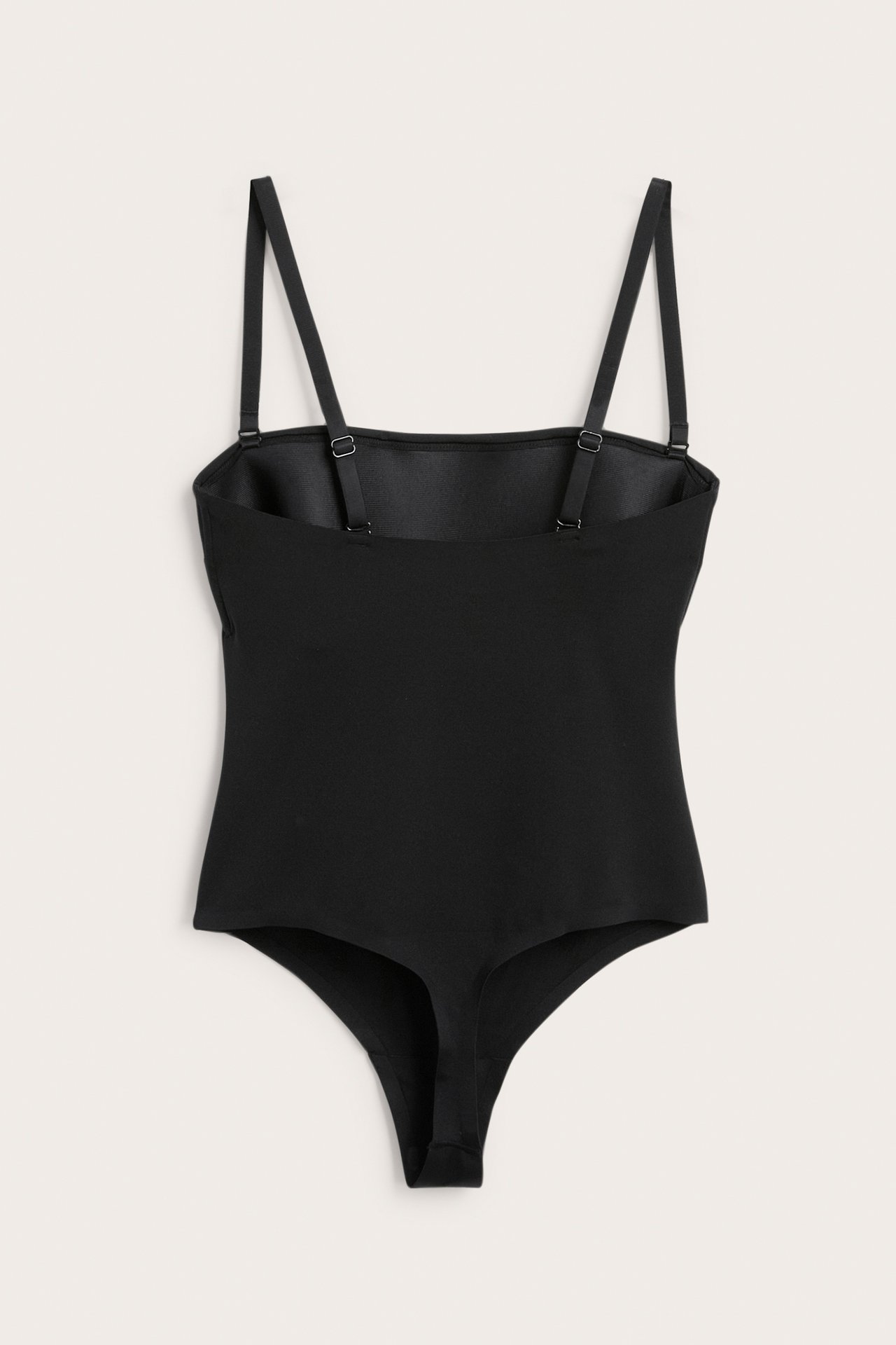 Frontvy av en svart vadderad stringbody i stretchigt microtyg med justerbara band.