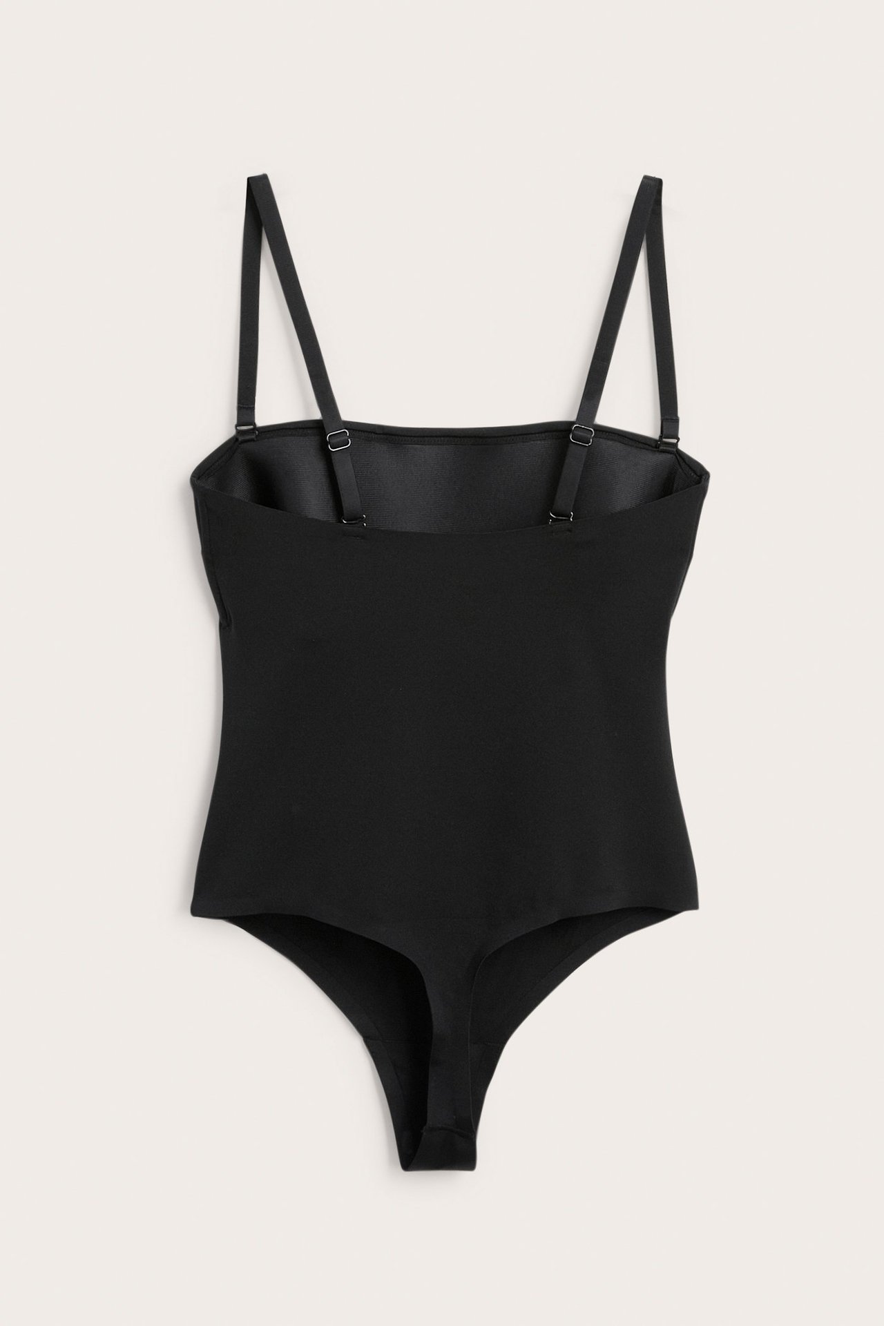 Frontvy av en svart vadderad stringbody i stretchigt microtyg med justerbara band.