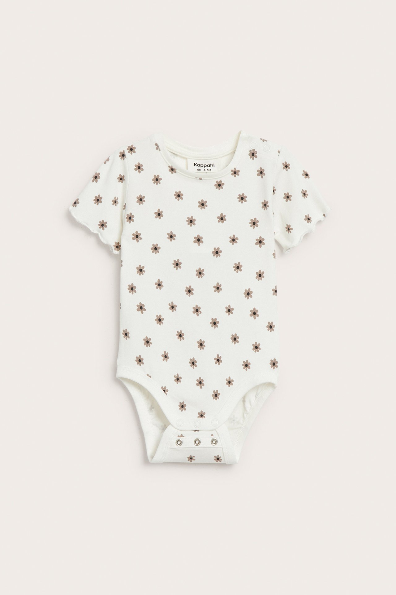 Framsida av offwhite kortärmad babybody med småblommigt mönster, tryckknappar vid axel och gren.