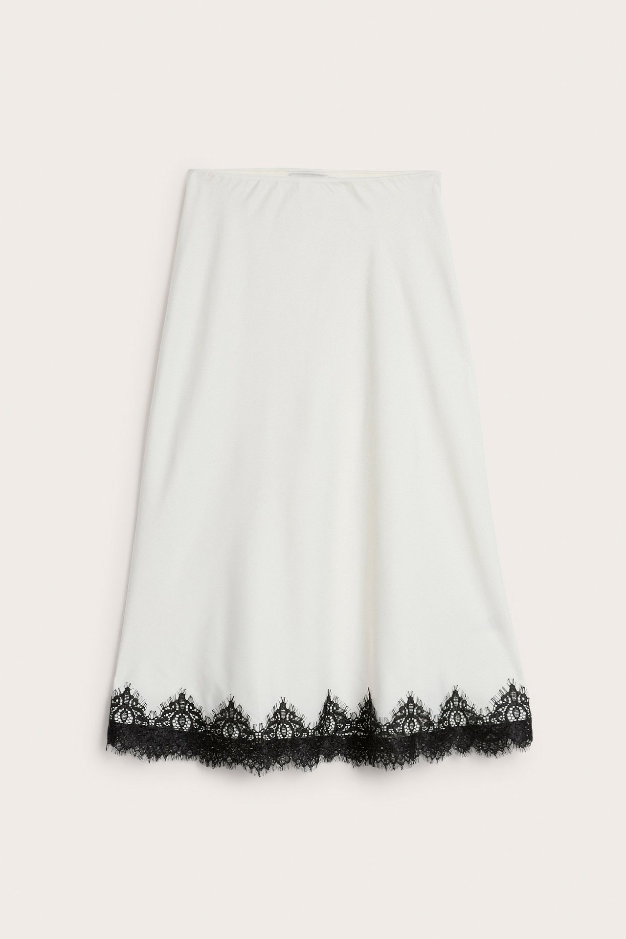 Frontbilde av et offwhite, flytende satinskjørt med en svart blondekant nederst.